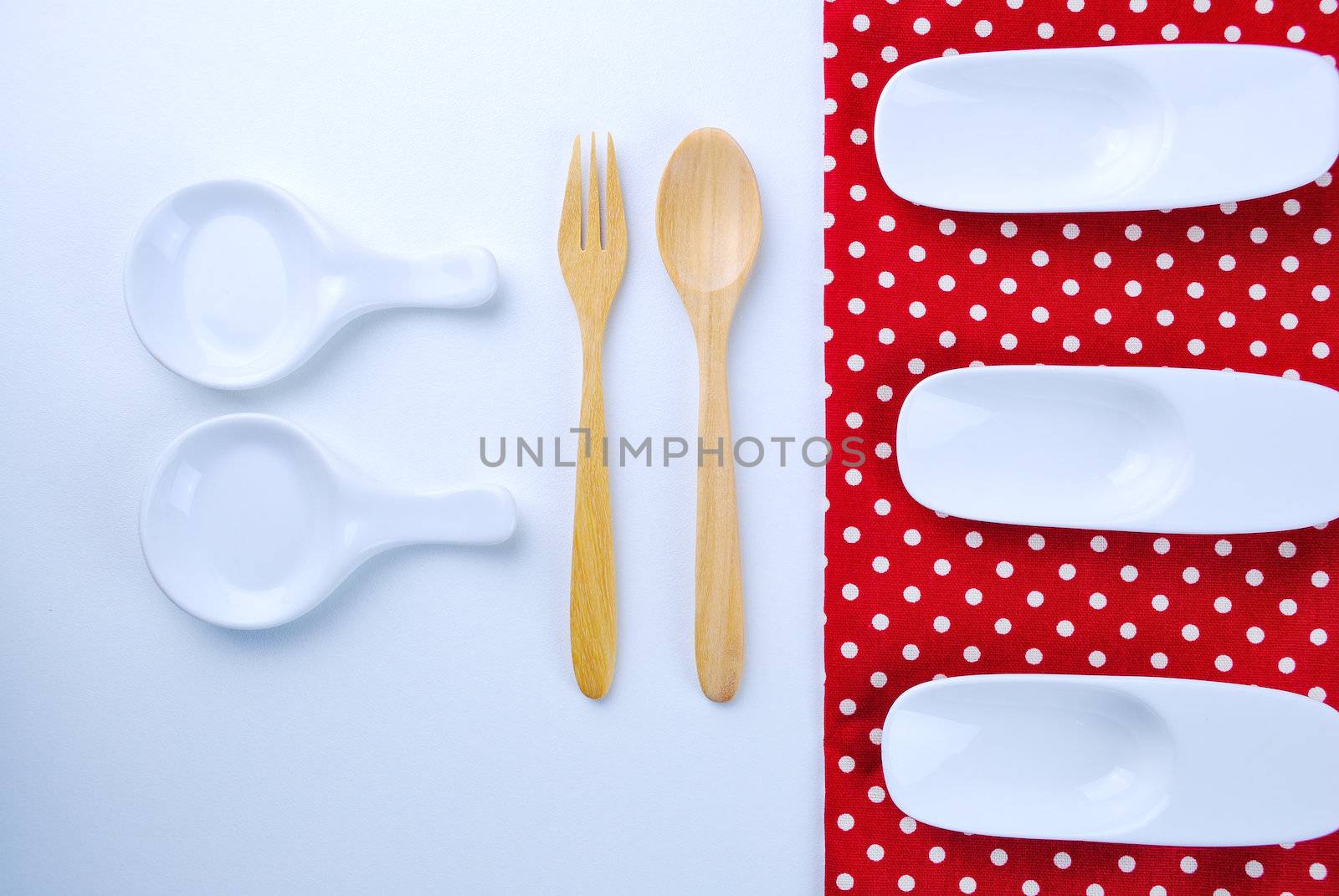 Wooden plate, tablecloth, spoon, fork on table background