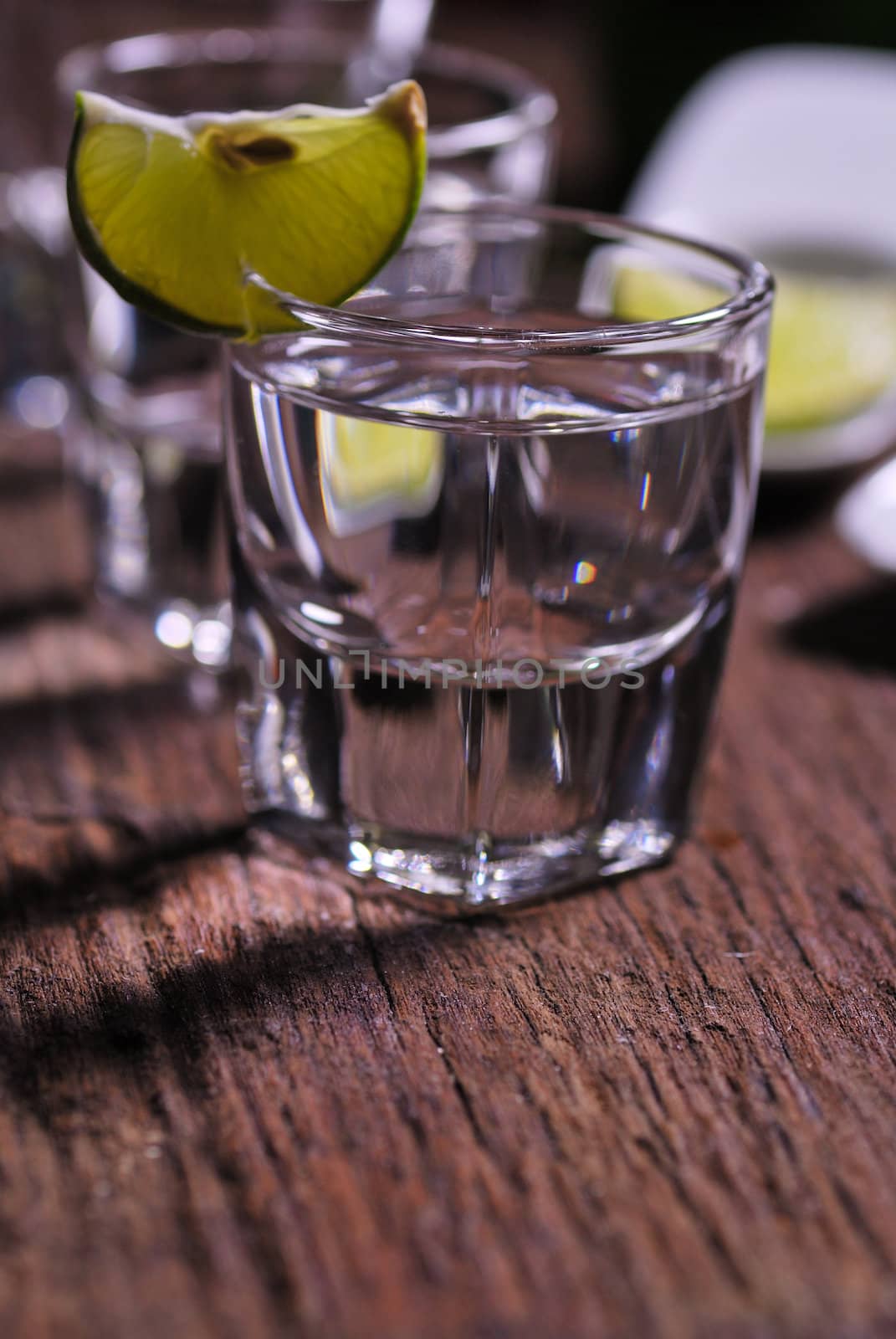 Glass of vodka shot with fresh lime on wooden table
