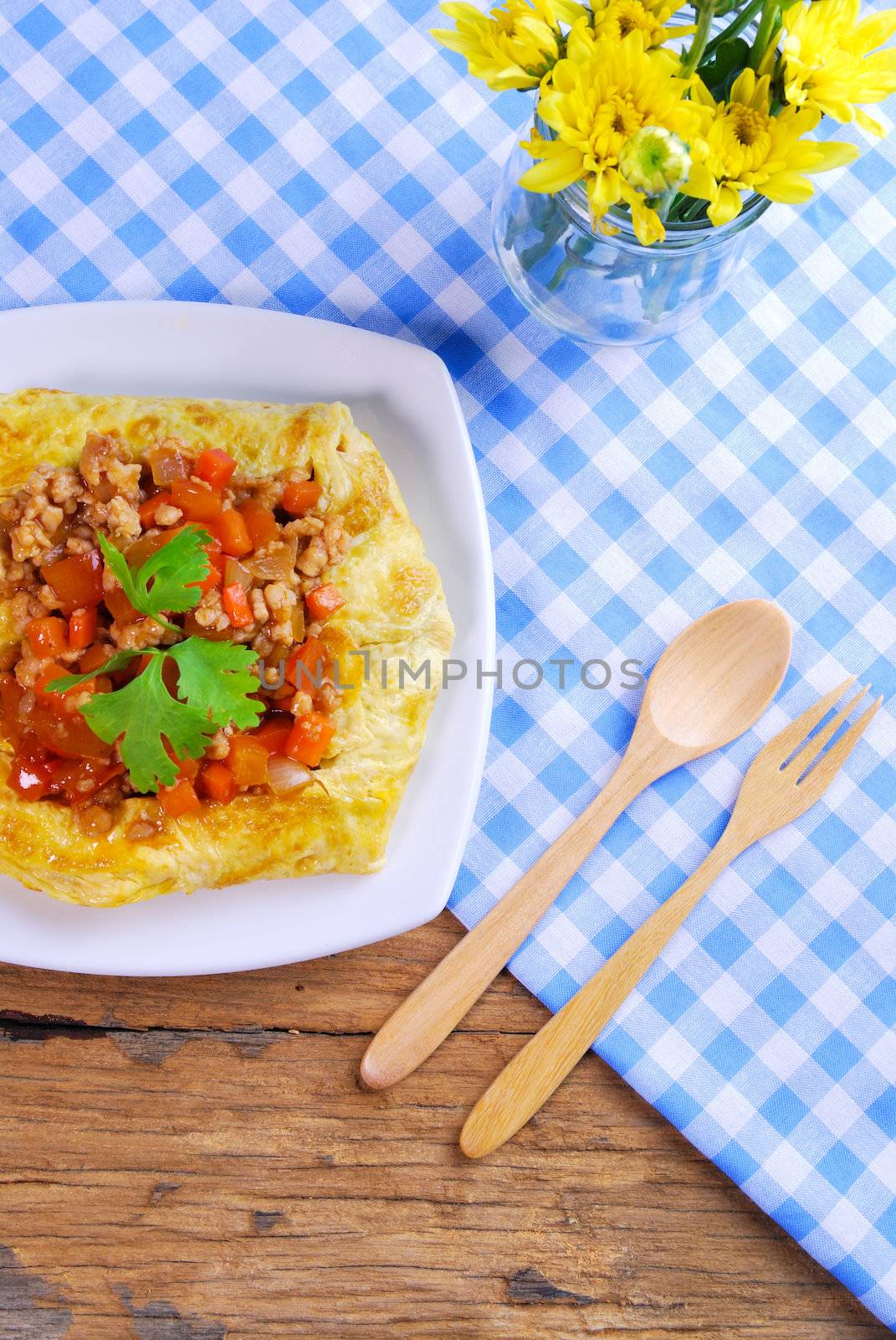 plate of stuffed omelette with tablecloth wooden spoon and fork