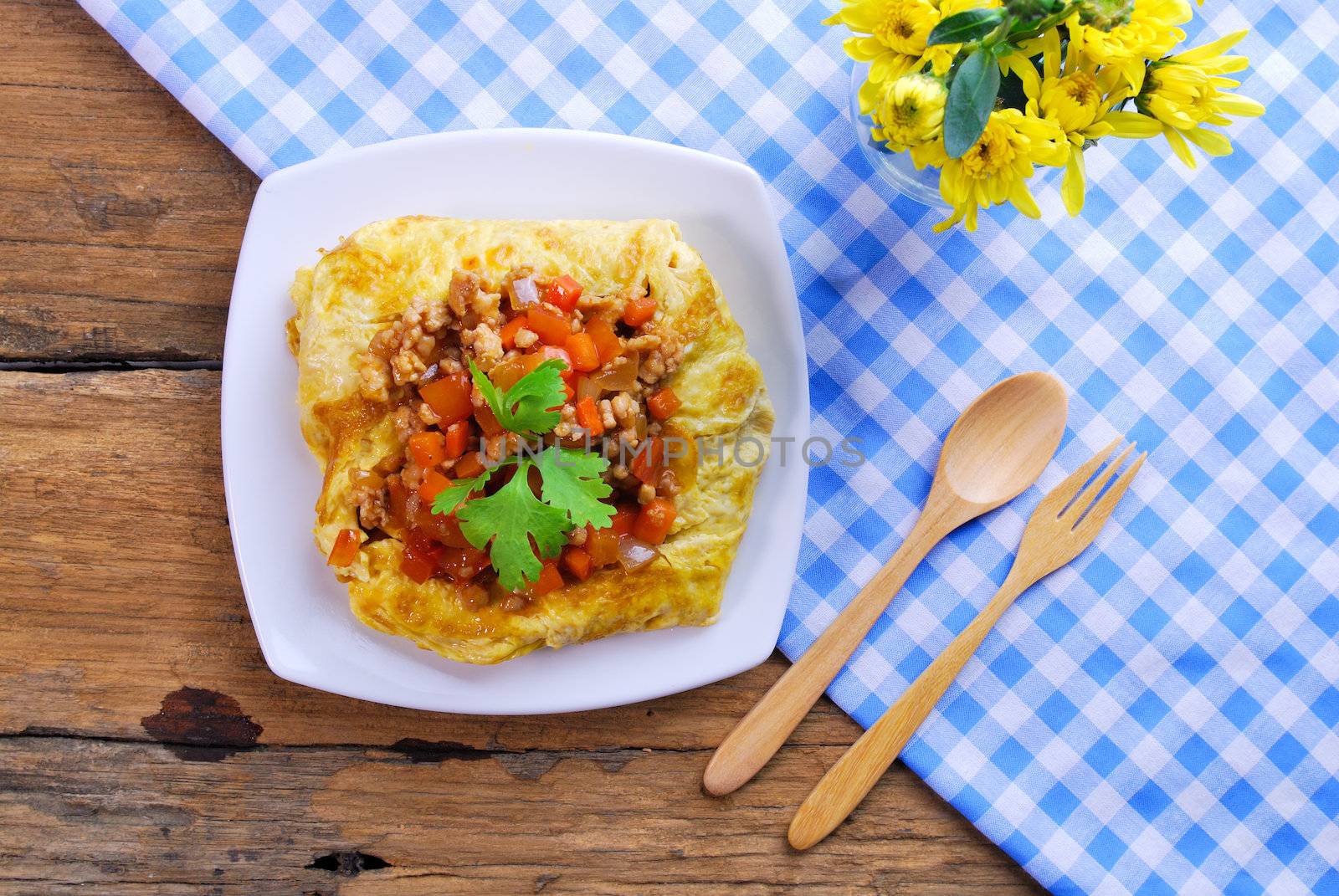 plate of stuffed omelette with tablecloth wooden spoon and fork