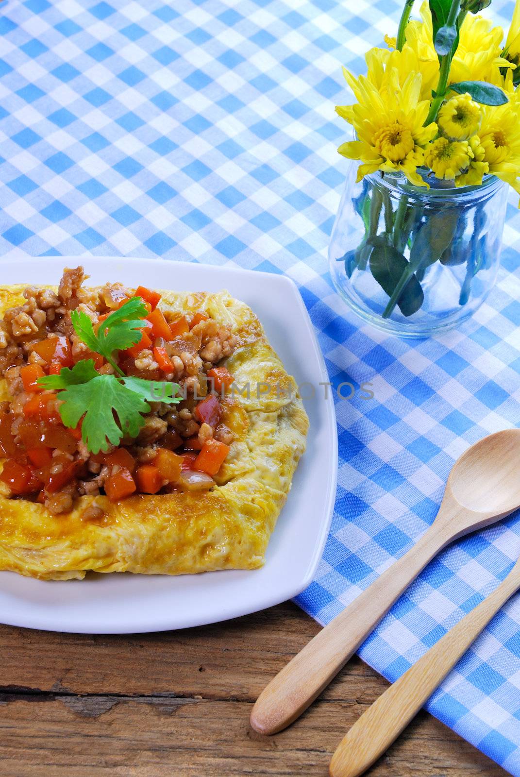 plate of stuffed omelette with tablecloth wooden spoon and fork by teen00000
