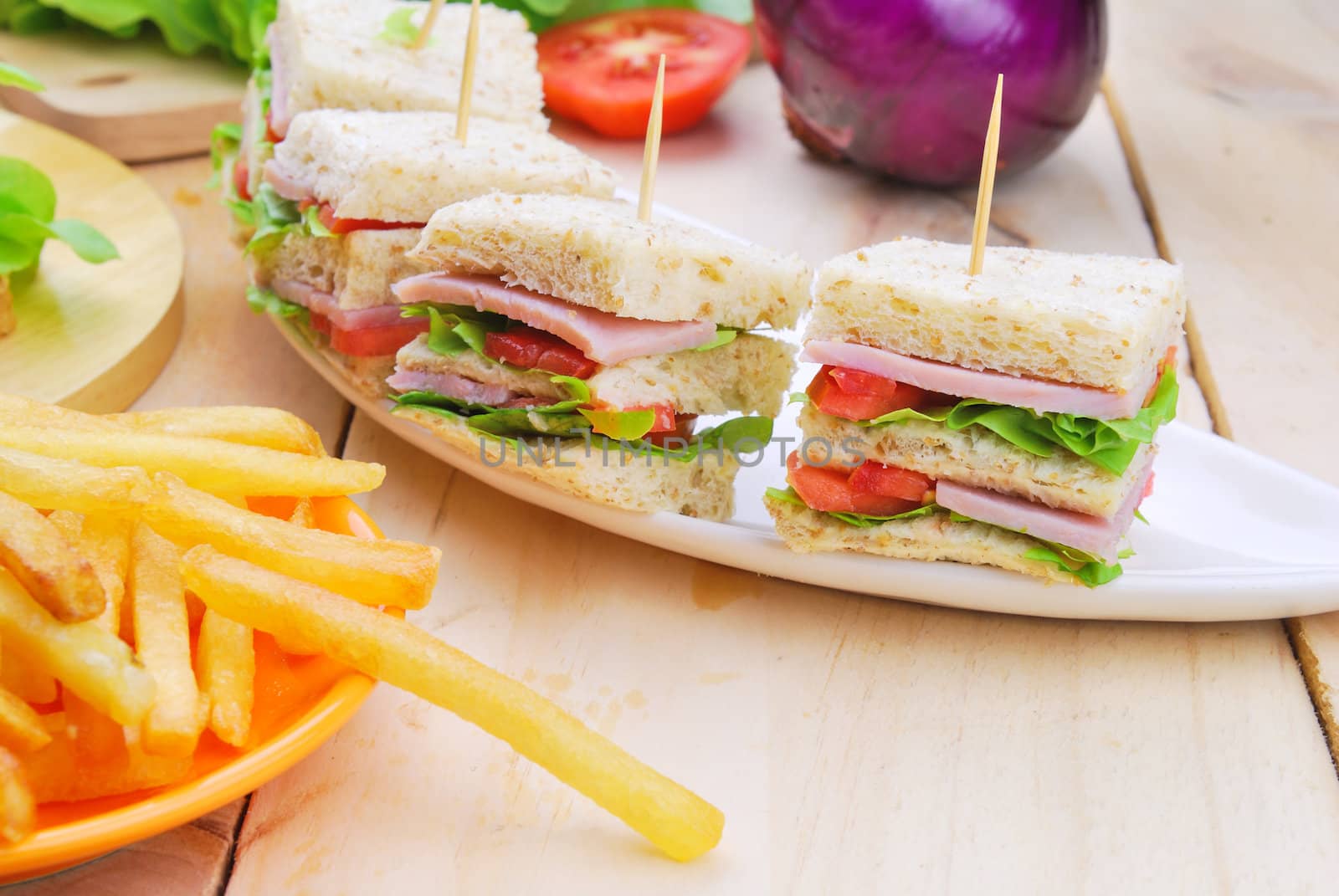 Club Sandwich with Cheese, Pickled Cucumber, Tomato and ham. Garnished with French Fries