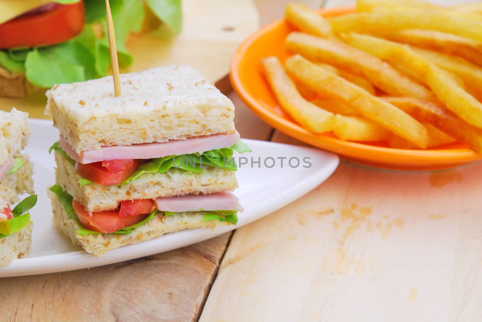 Club Sandwich with Cheese, Pickled Cucumber, Tomato and ham. Garnished with French Fries