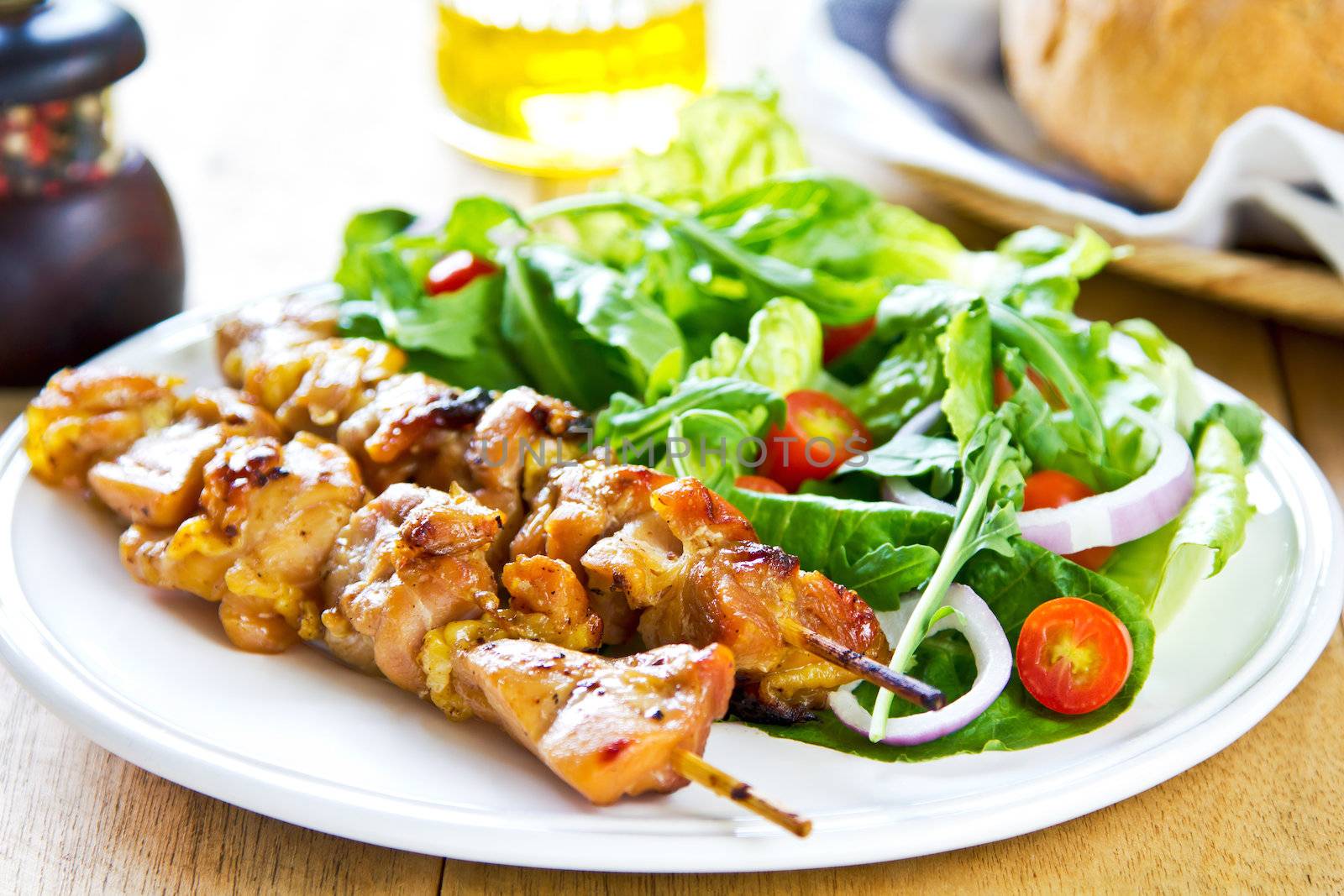 Grilled chicken skewer with rocket salad by bread