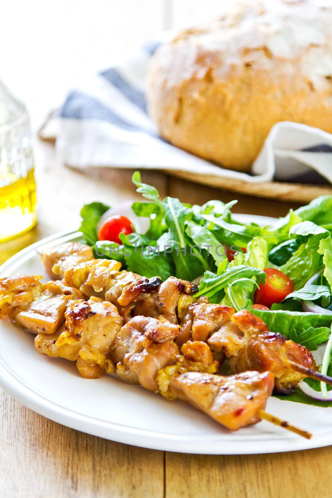 Grilled chicken skewer with rocket salad by bread