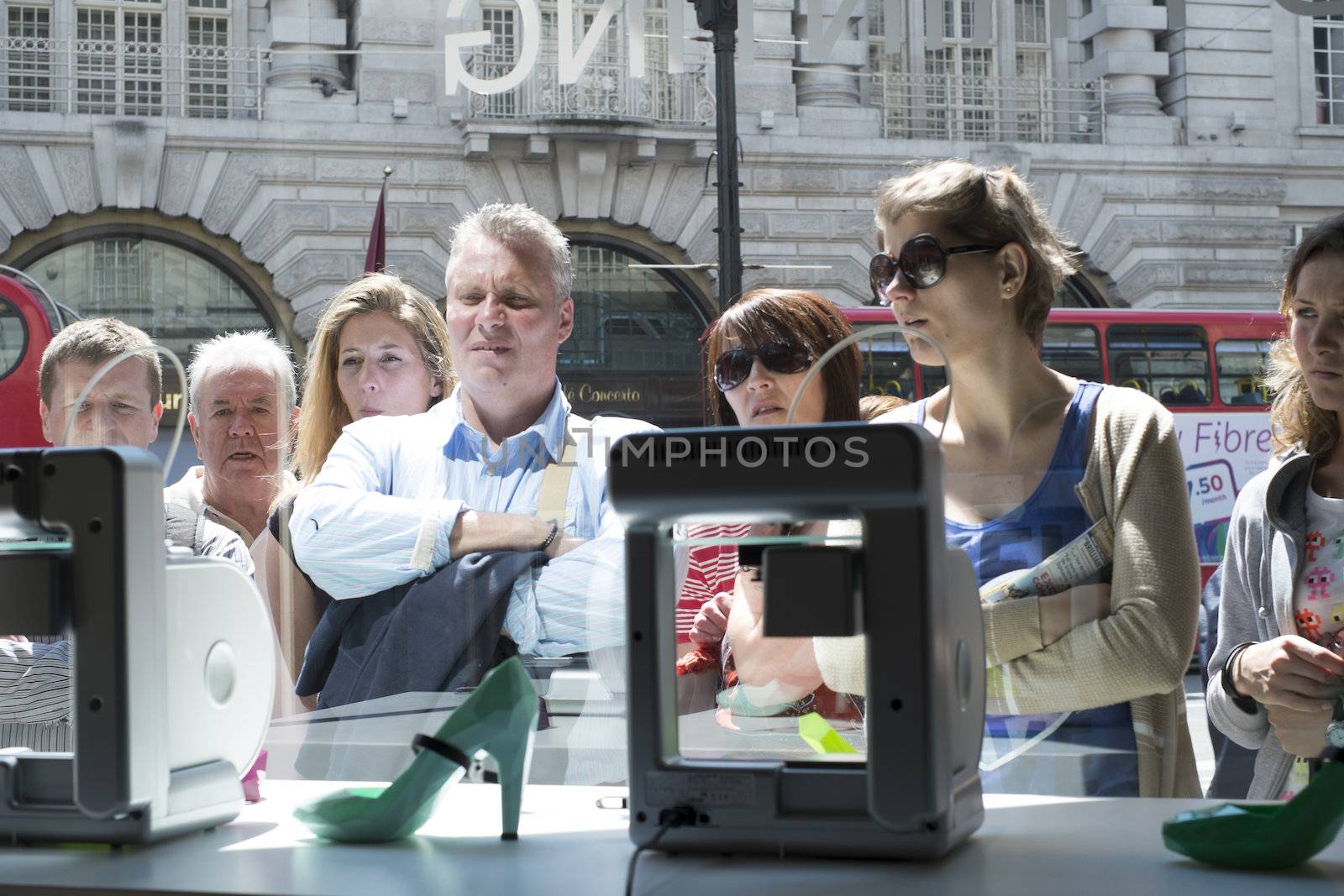 LONDON, UK - MAY 31: Pedestrians intrigued with 3D printer in United Nude shop window. The shop, based in Regent Street, has a line of products created on site by 3D printers. May 31, 2014 in London.