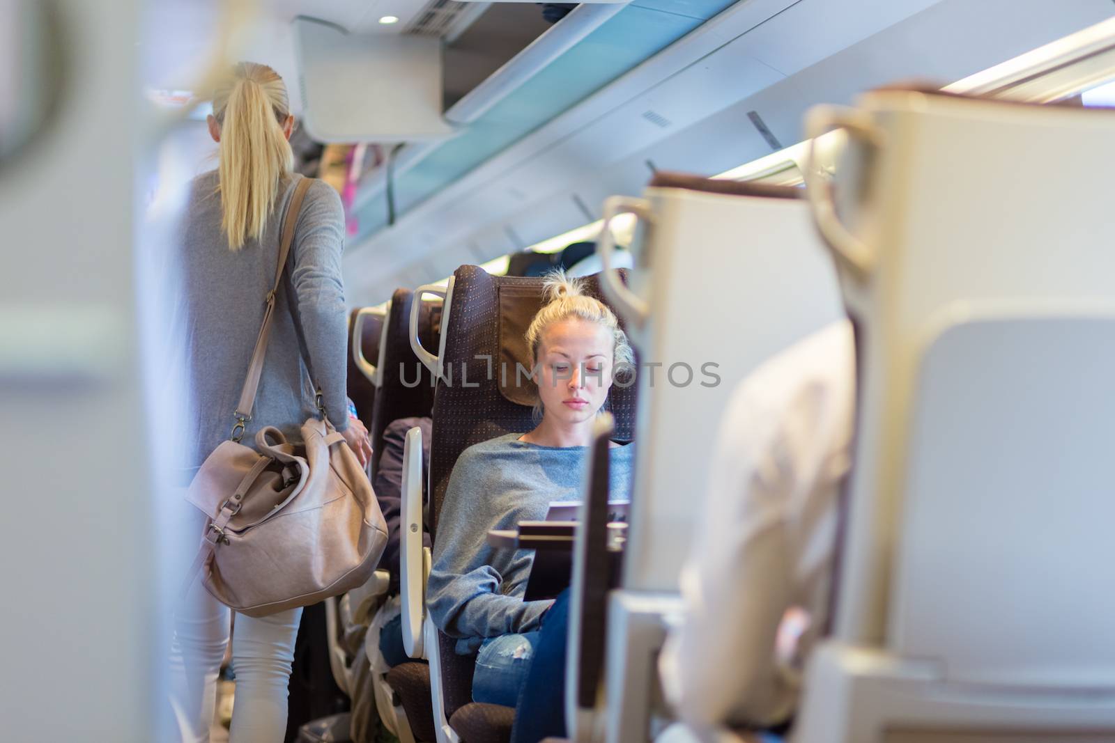 Blonde casual caucasian lady traveling by train. Train full of passengers going to work by public transport at rush hour.