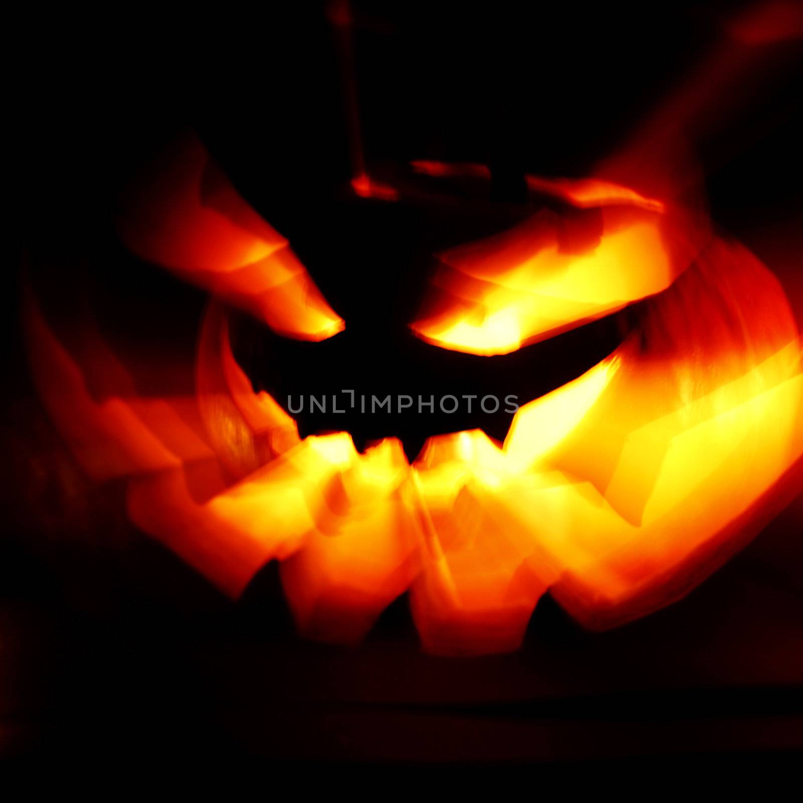 Glowing Halloween pumpkin with rays of light on black background