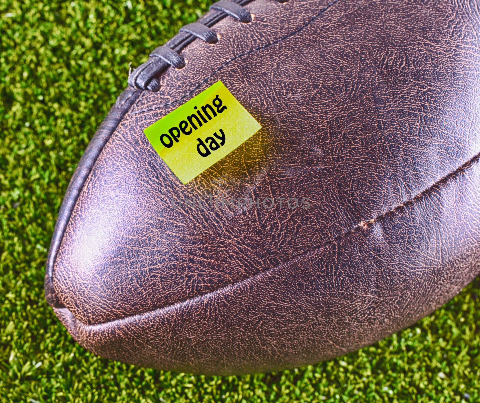 Football with yellow note telling "Opening day", over grass