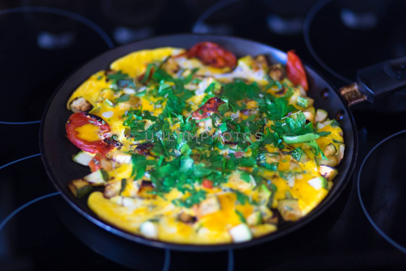 Omelet with vegetables in pan on elecric stove.
