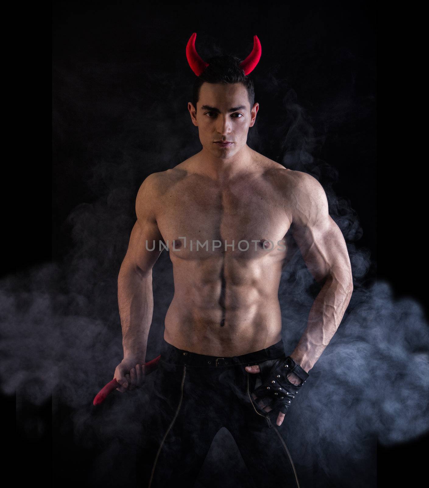Sexy Handsome Man Wearing Devilish Horn Accessories Showing Muscled Body. Isolated on Smoky Background.