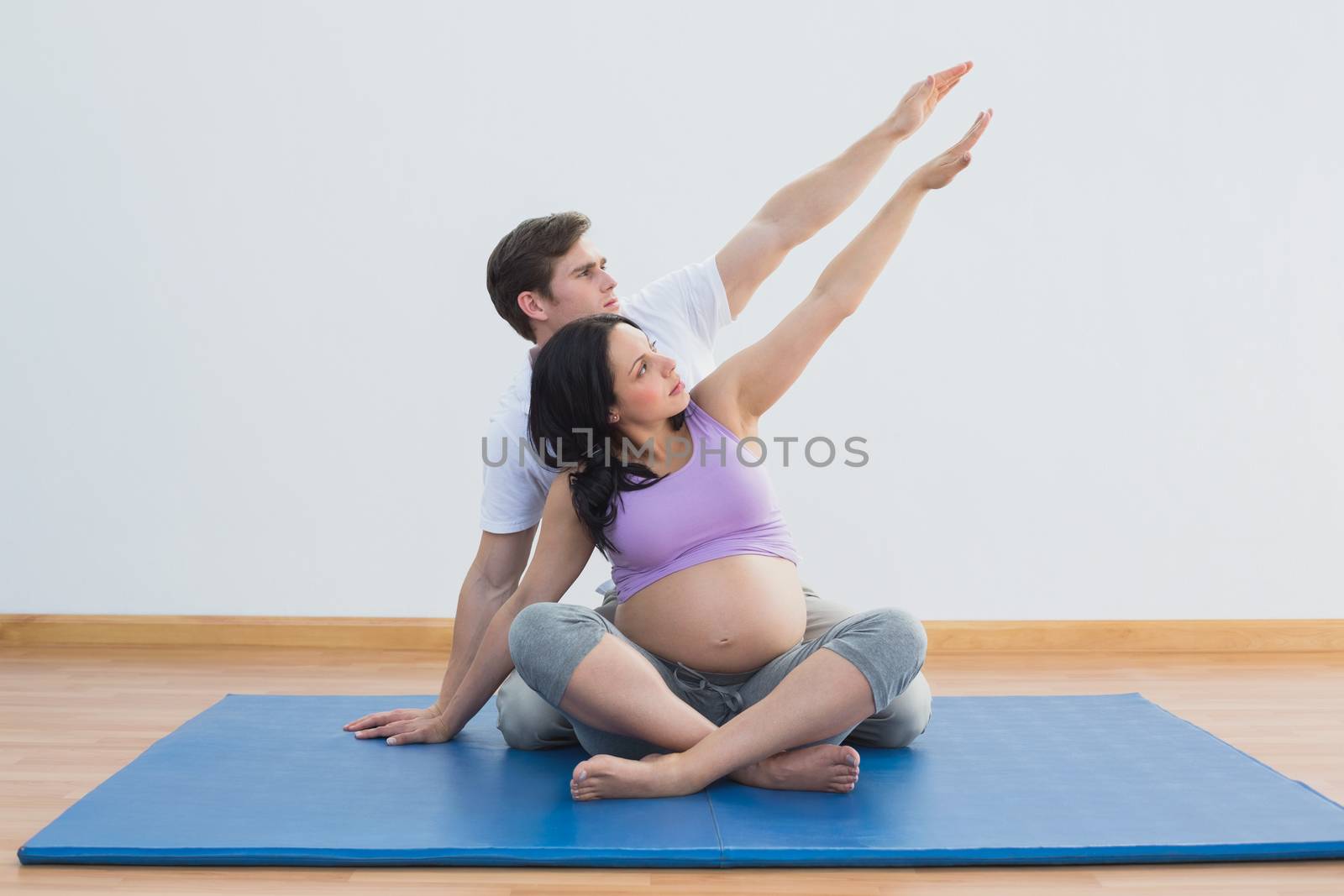 Trainer sitting with pregnant woman doing yoga by Wavebreakmedia