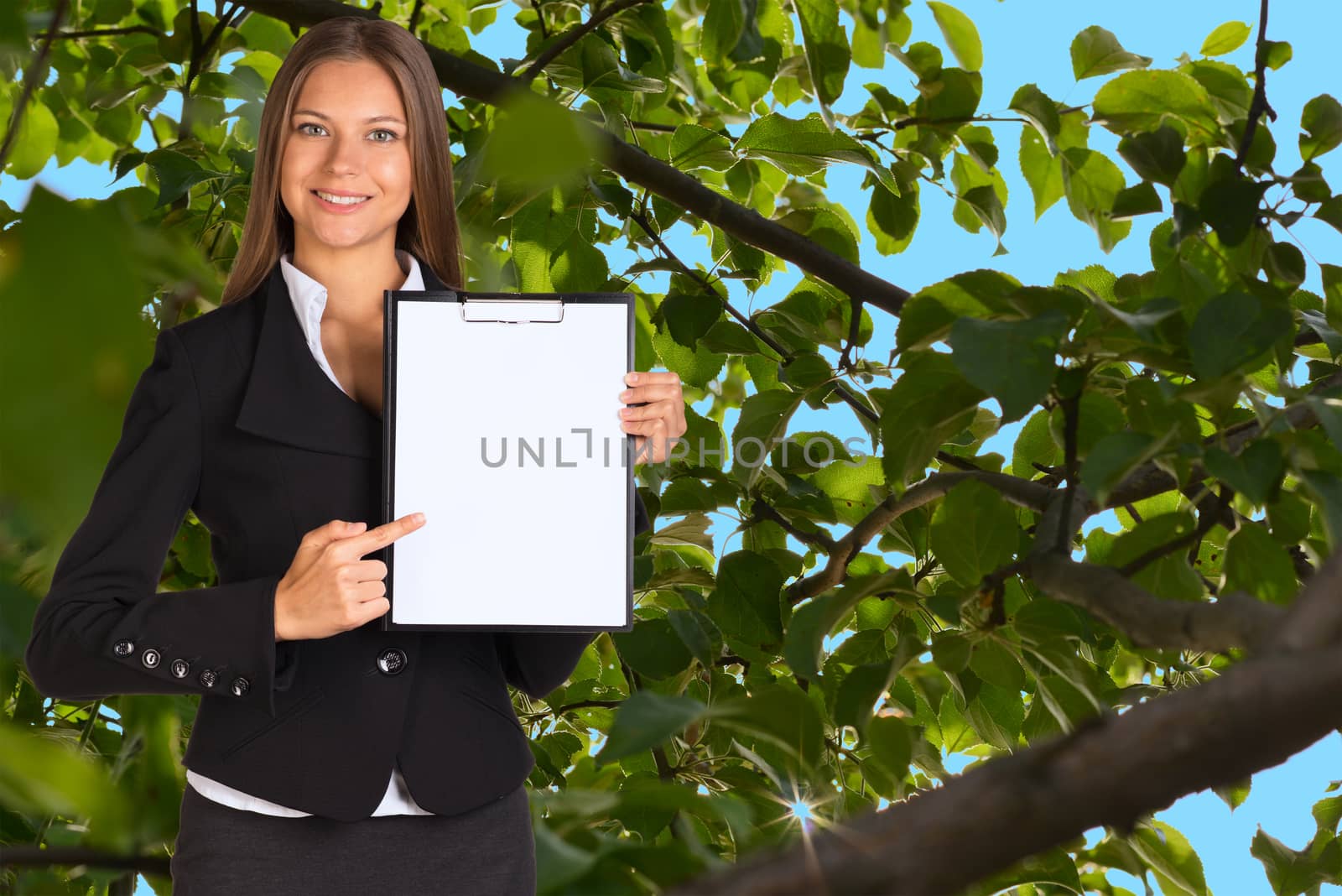 Businesswoman holding paper holder. Green leaves and brown branches of a tree as backdrop