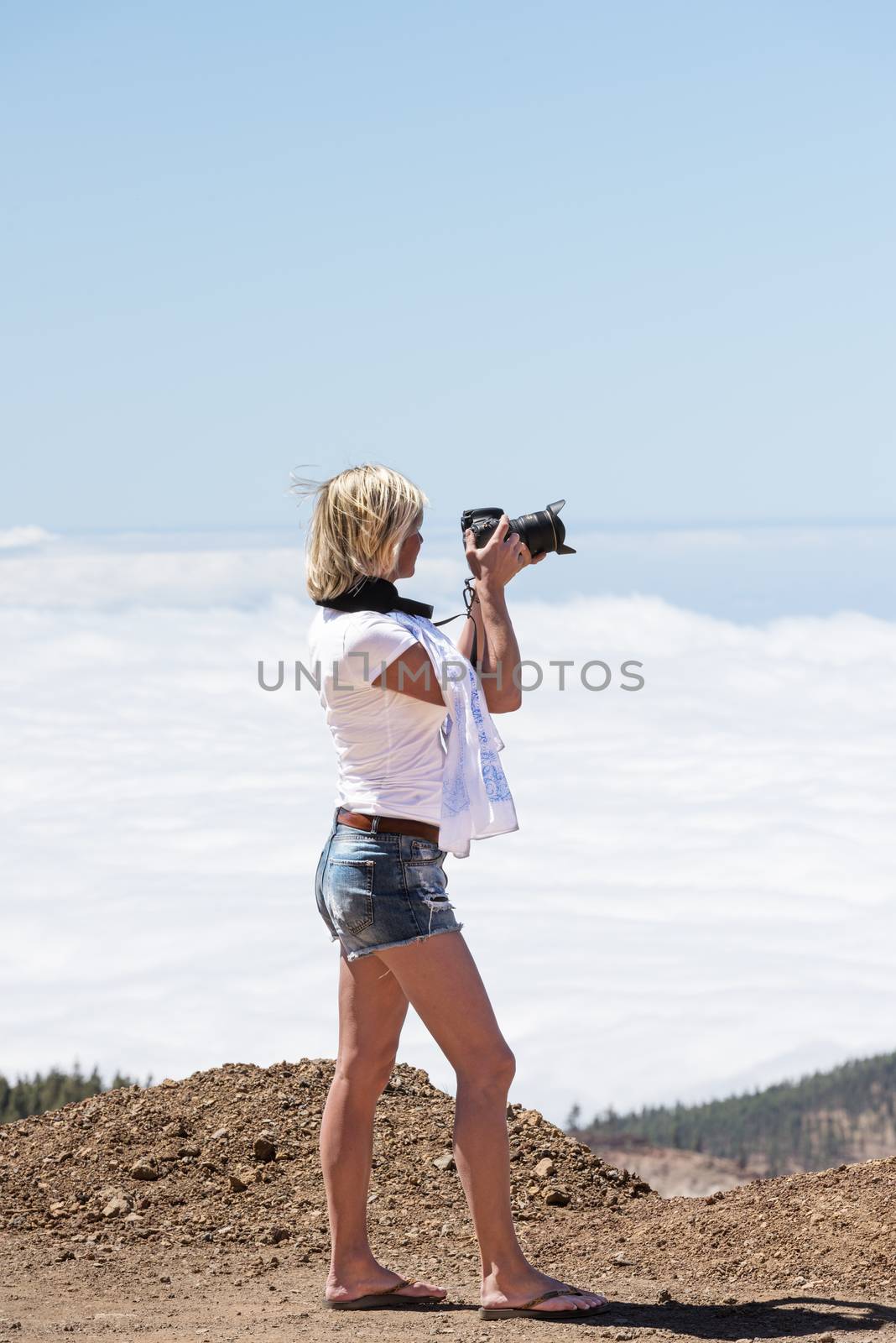 Young woman with camera above clouds