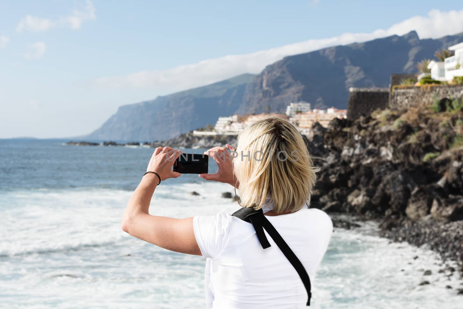 Woman taking picture on mobile phone at Los Gigantes, Tenerife, Spain