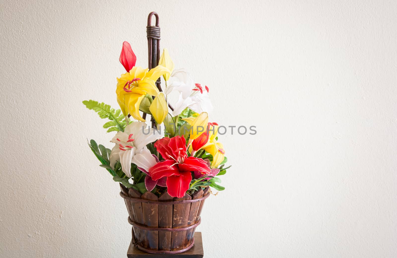 the colouful flowers with green leaves in the wooden jar