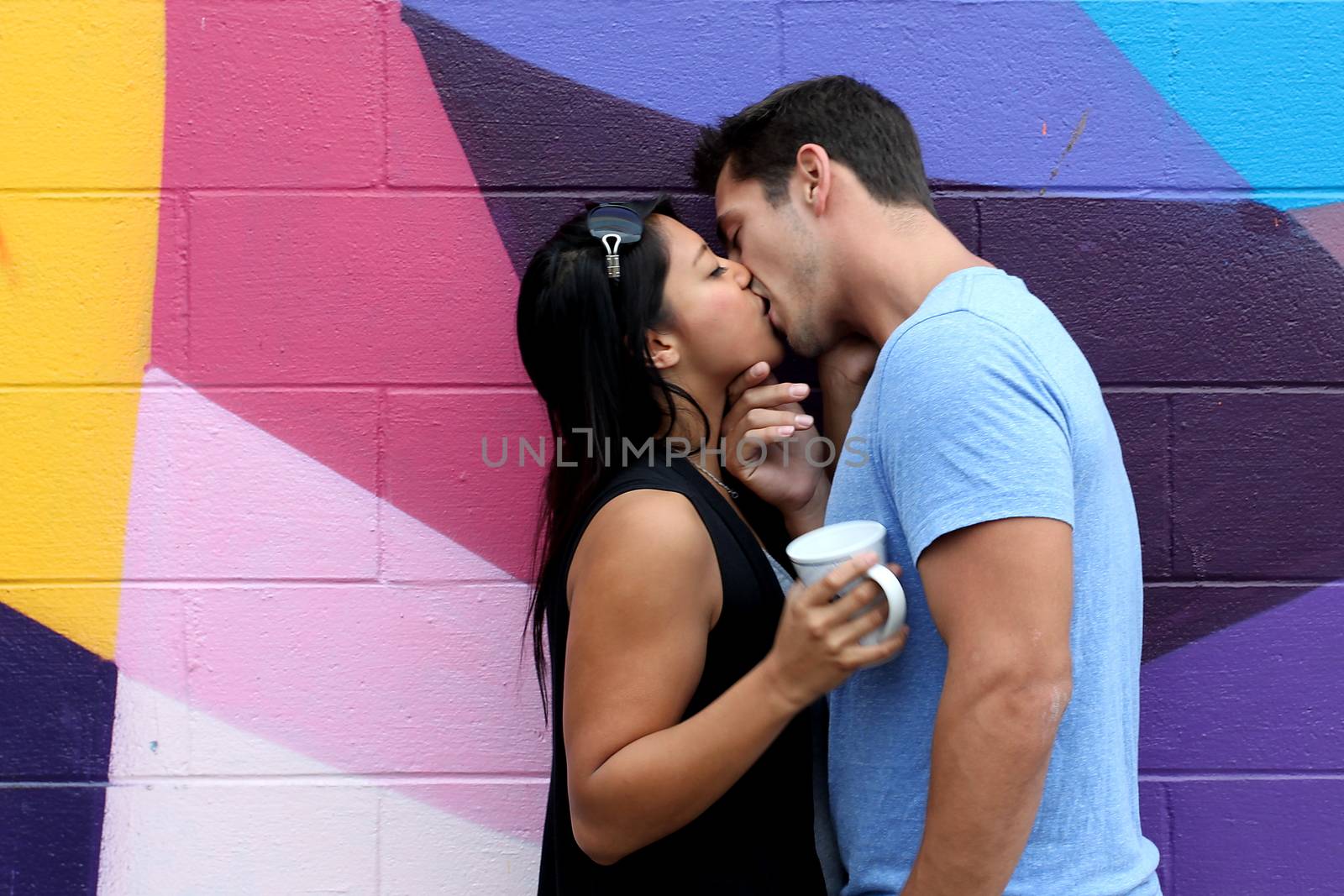 A in love couple kissing in front of a wall.