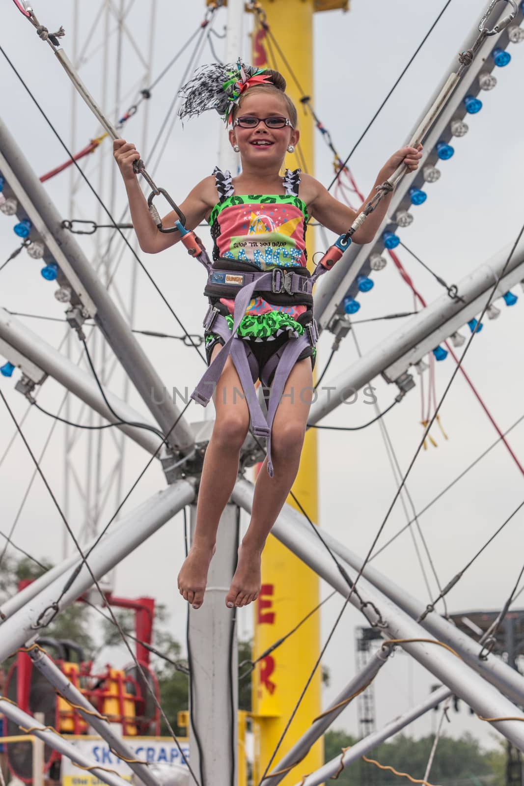 DES MOINES, IA /USA - AUGUST 10: Attendees at the Unidentified girl on carnival jumping apparatus at the Iowa State Fair on August 10, 2014 in Des Moines, Iowa, USA.