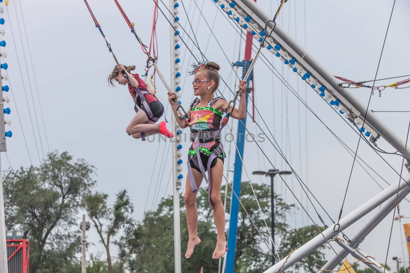 DES MOINES, IA /USA - AUGUST 10: Unidentified girls jumping in harnesses on carnival jumping apparatus at the Iowa State Fair on August 10, 2014 in Des Moines, Iowa, USA.