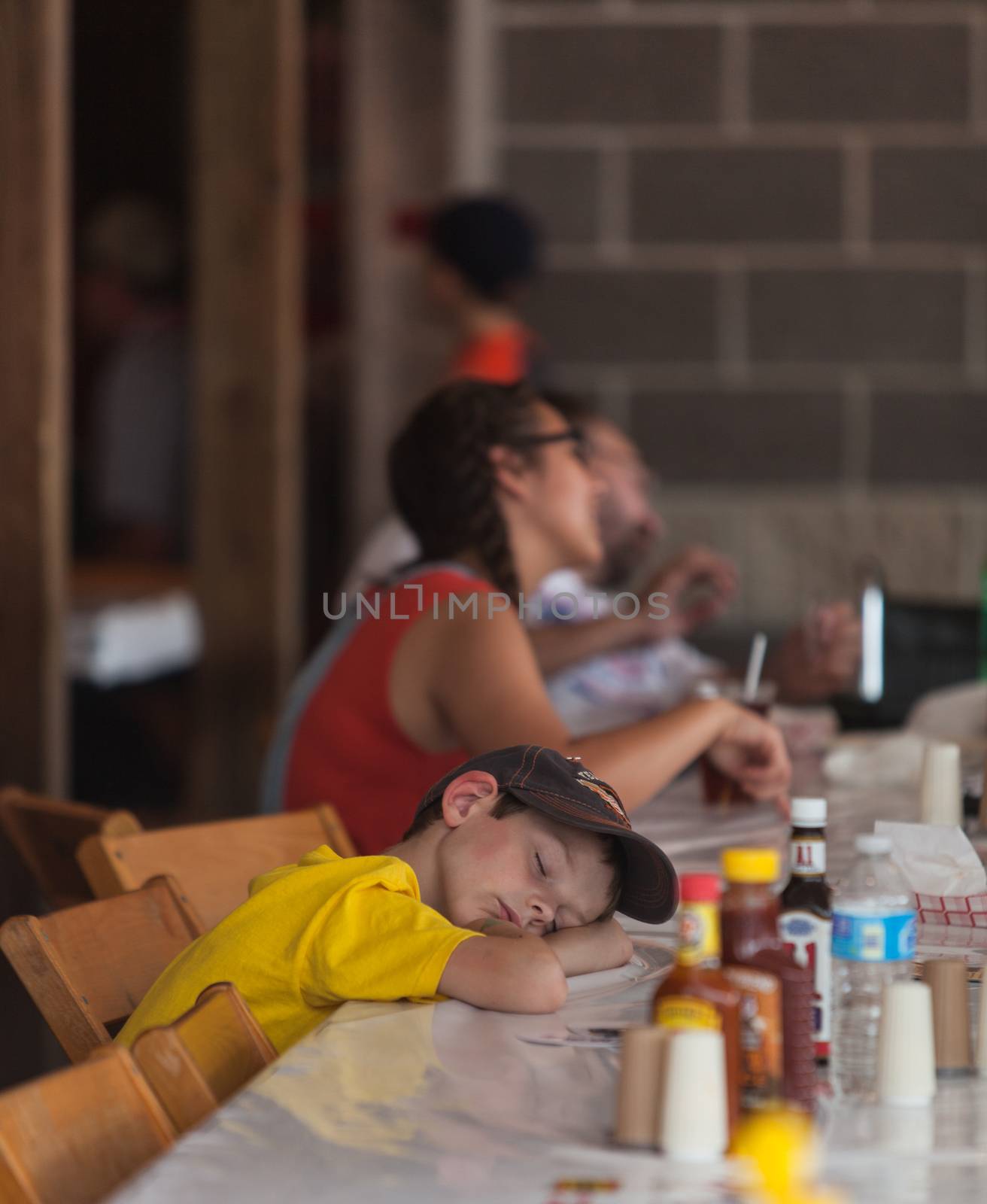 DES MOINES, IA /USA - AUGUST 10: Unidentified tired boy rests head on table at the Iowa State Fair on August 10, 2014 in Des Moines, Iowa, USA.