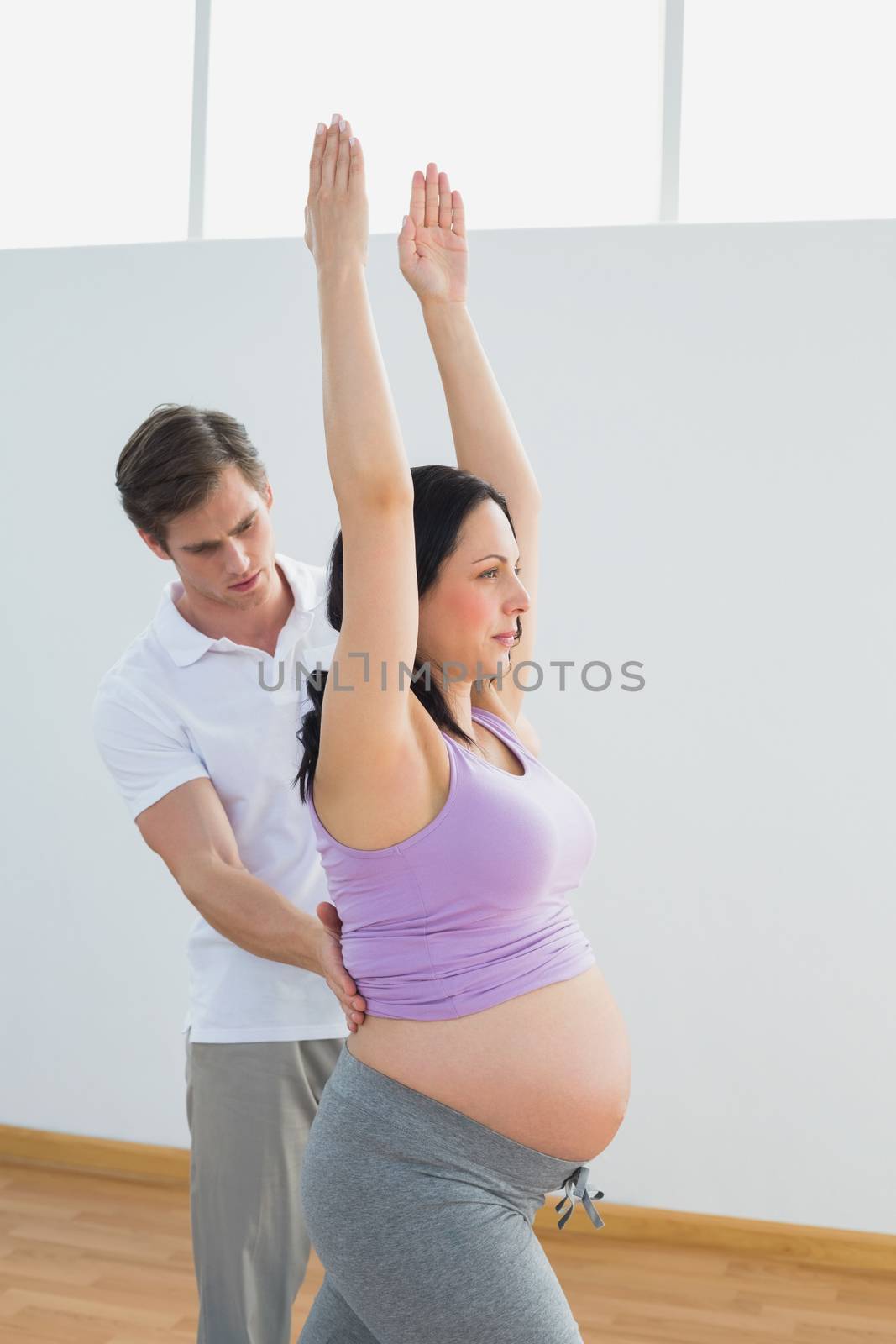 Breathing pregnant woman doing yoga with a personal trainer by Wavebreakmedia