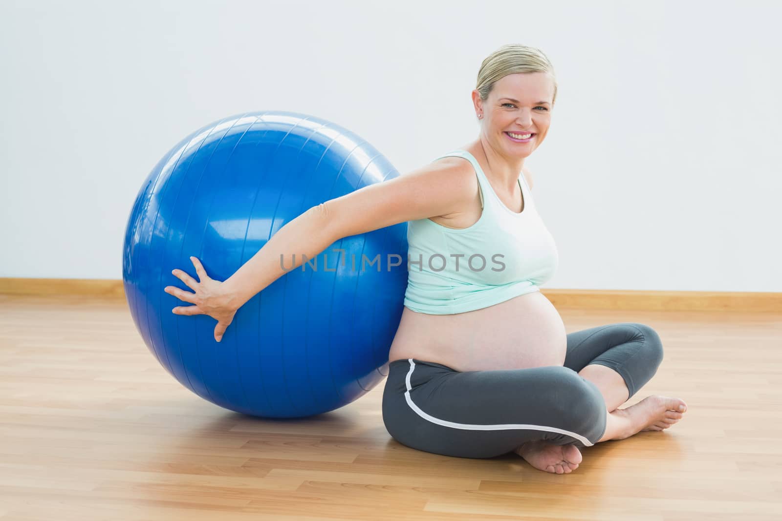 Happy pregnant woman sitting beside exercise ball  by Wavebreakmedia