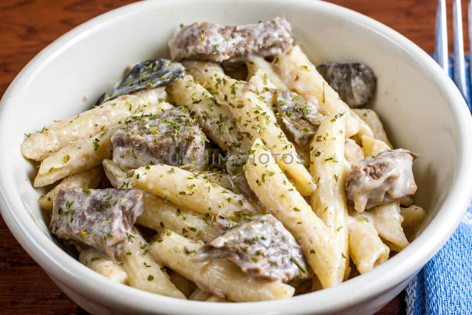 A bowl of rustic beef stroganoff on a wooden table.