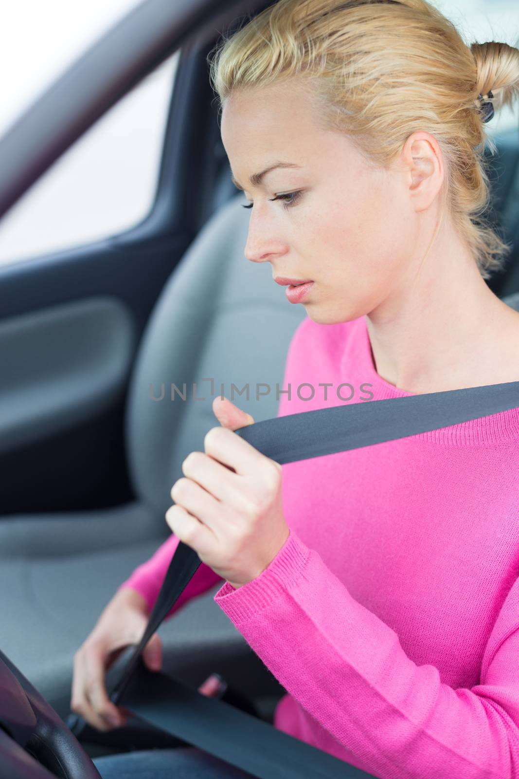 Beautiful woman fastening seat belt. by kasto