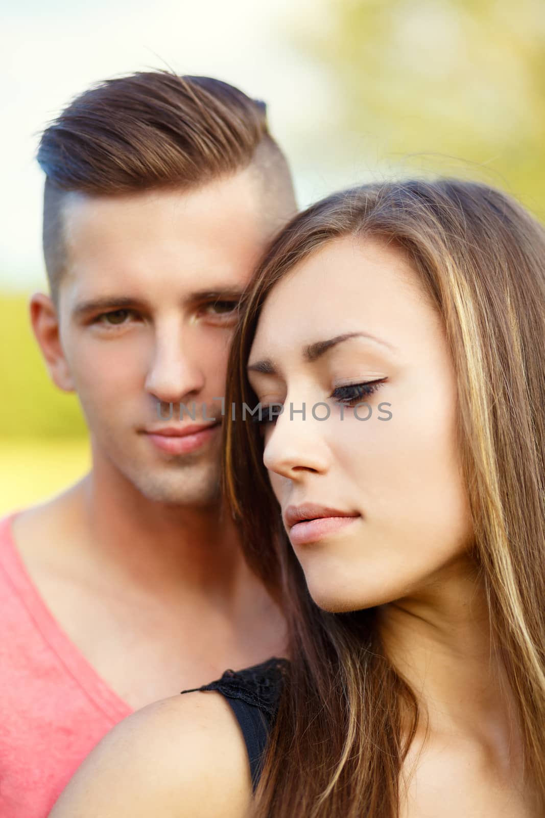 Happy smiling young couple embracing outdoor at sunny day