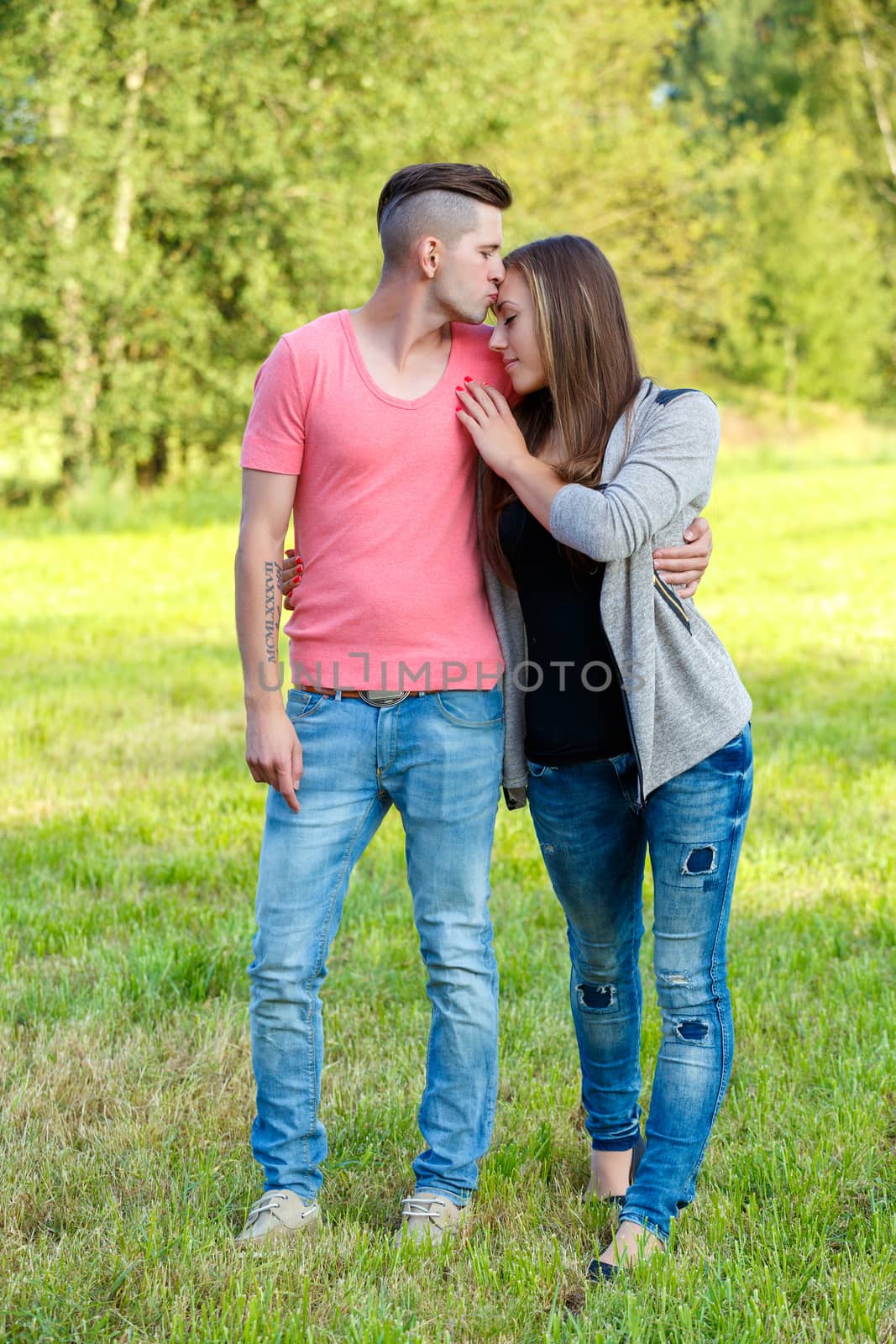 Happy kissing young couple embracing outdoor at sunny day