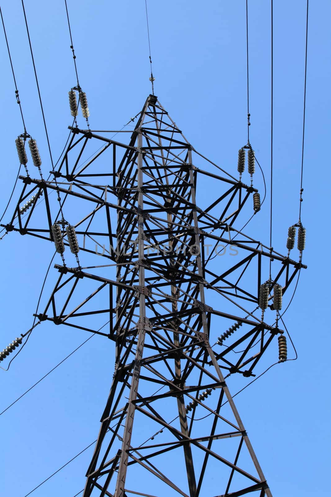 Power lines and electricity pylon  against blue sky