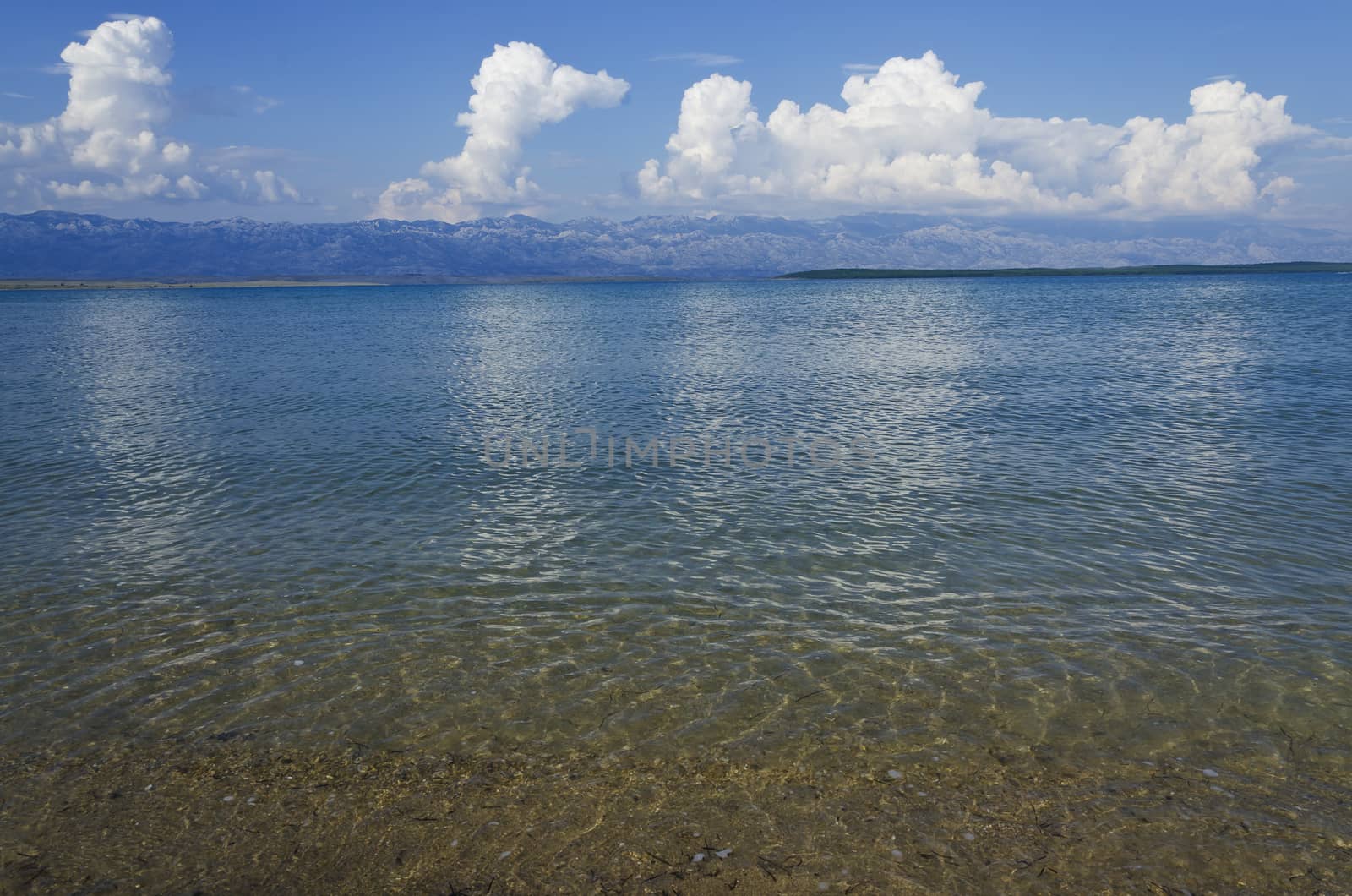 landscape of an empty sand beach in the summer day with clouds and mountains in the background
