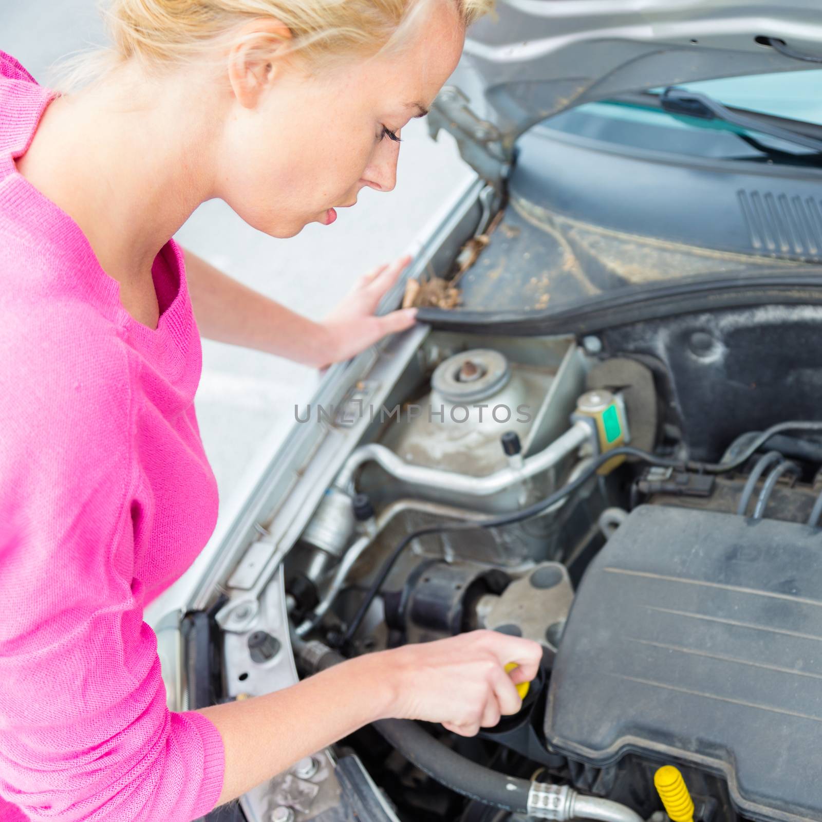 Woman inspecting broken car engine. by kasto