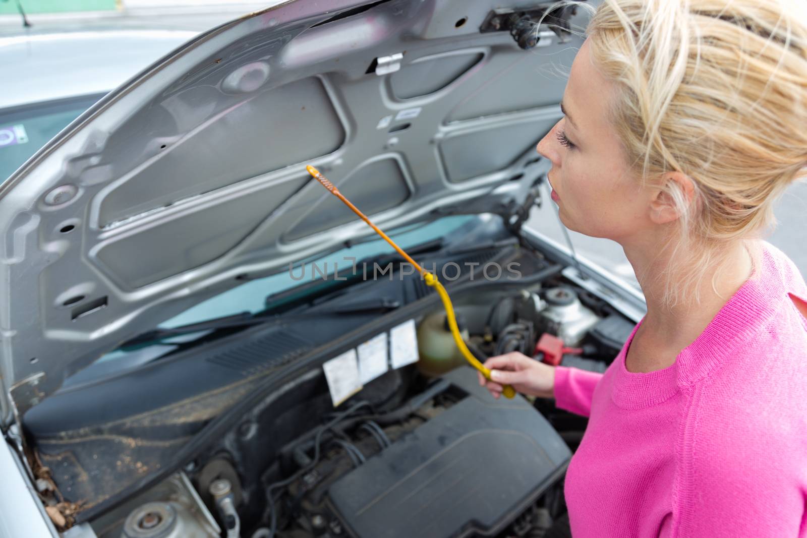 Woman inspecting broken car engine. by kasto