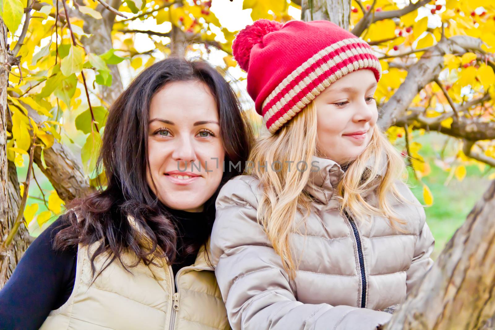 Photo of mother and daughter in autumn sitting on tree