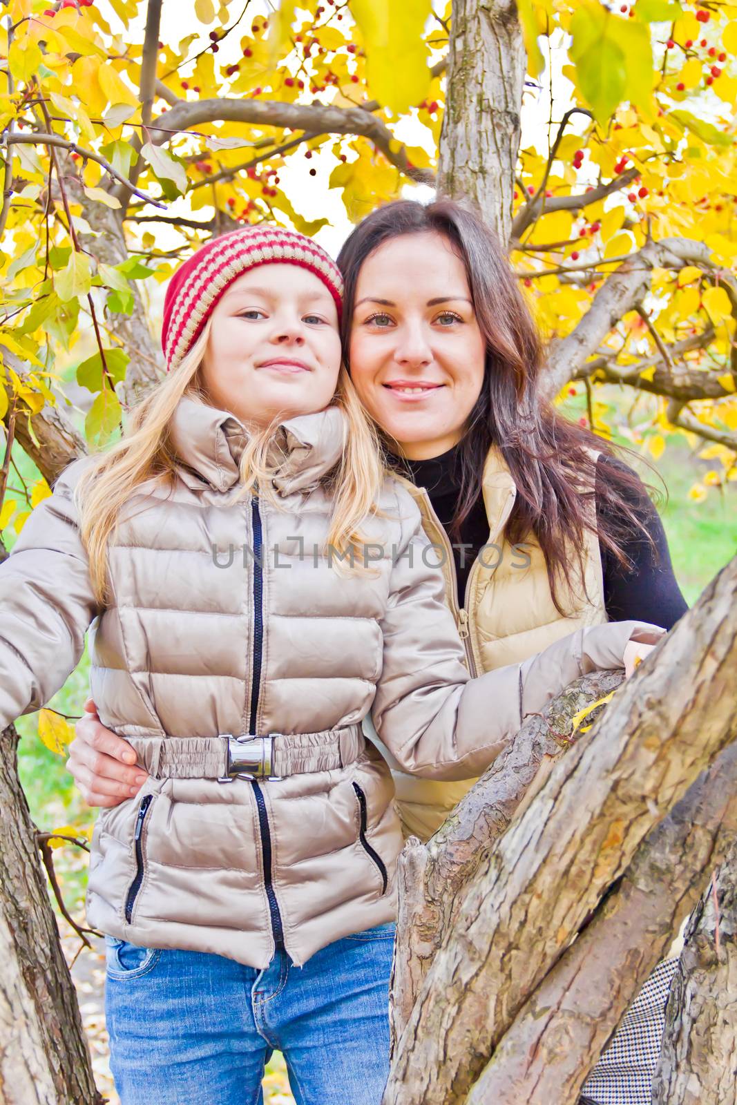 Photo of mother and daughter in autumn sitting on tree