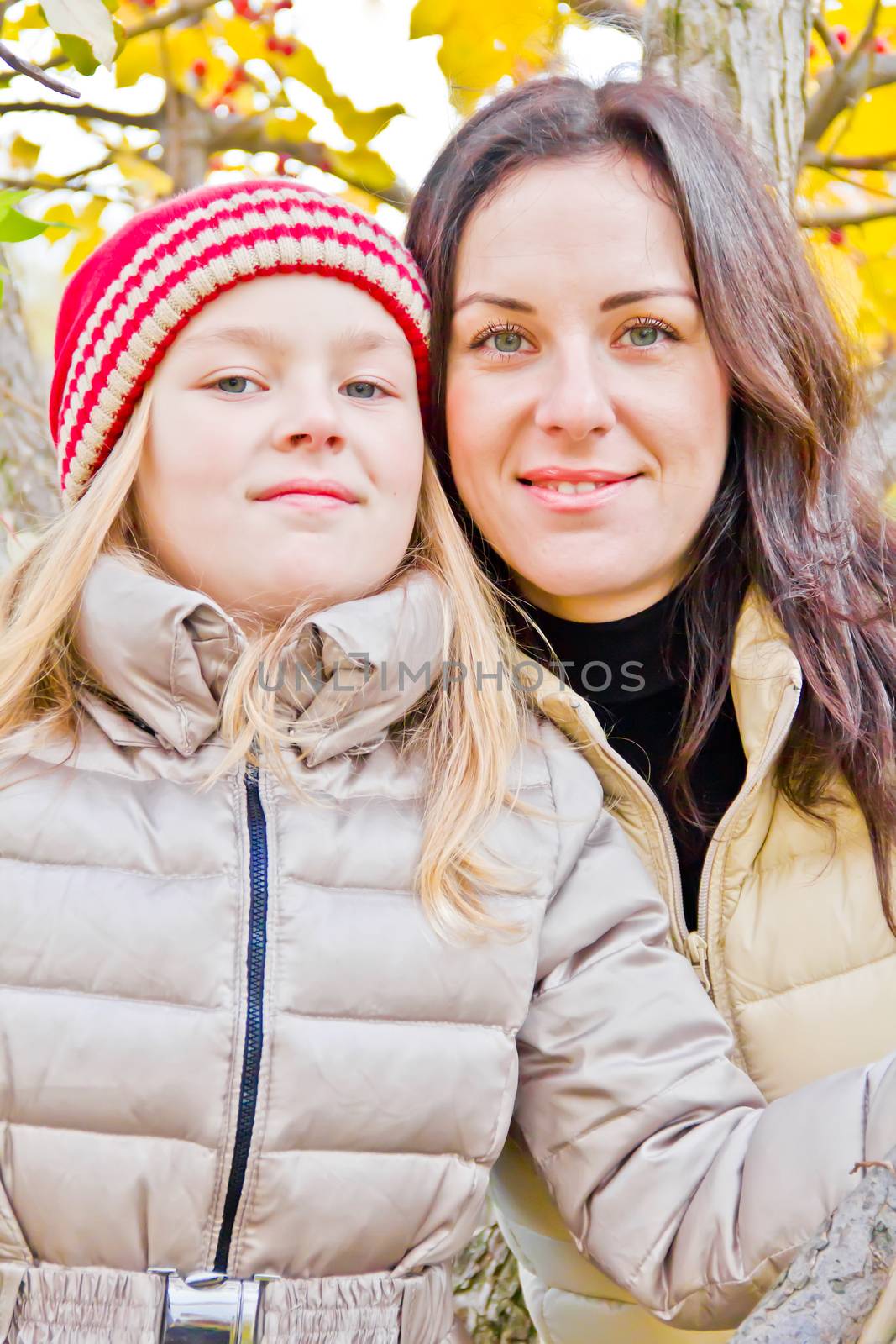 Photo of mother and daughter in autumn sitting on tree