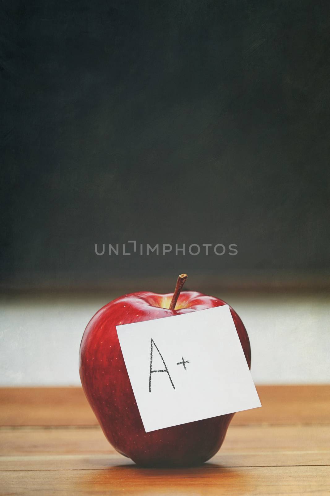  Red apple with note on desk with blackboard by Sandralise