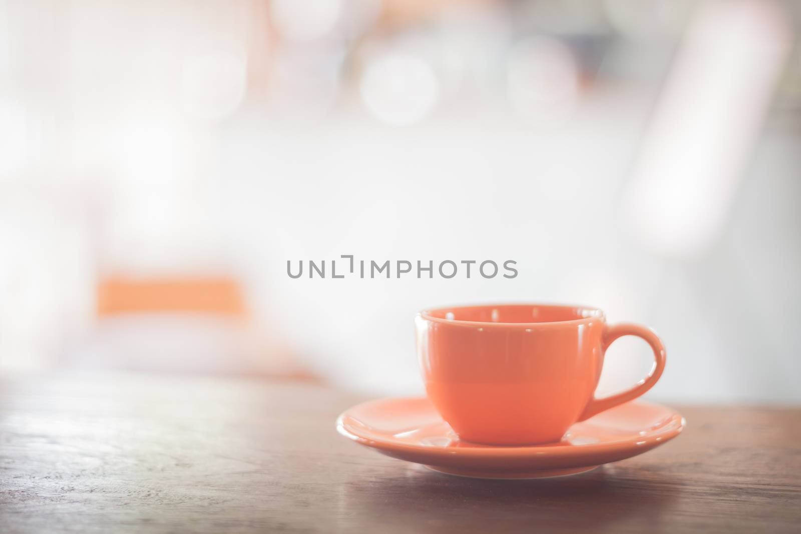 Mini orange coffee cup on wooden table, stock photo