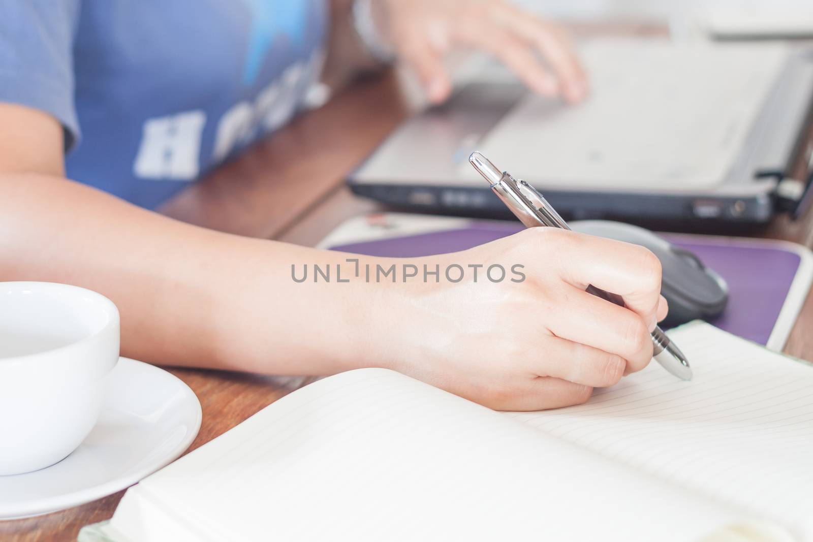 Woman writing on notebook, stock photo