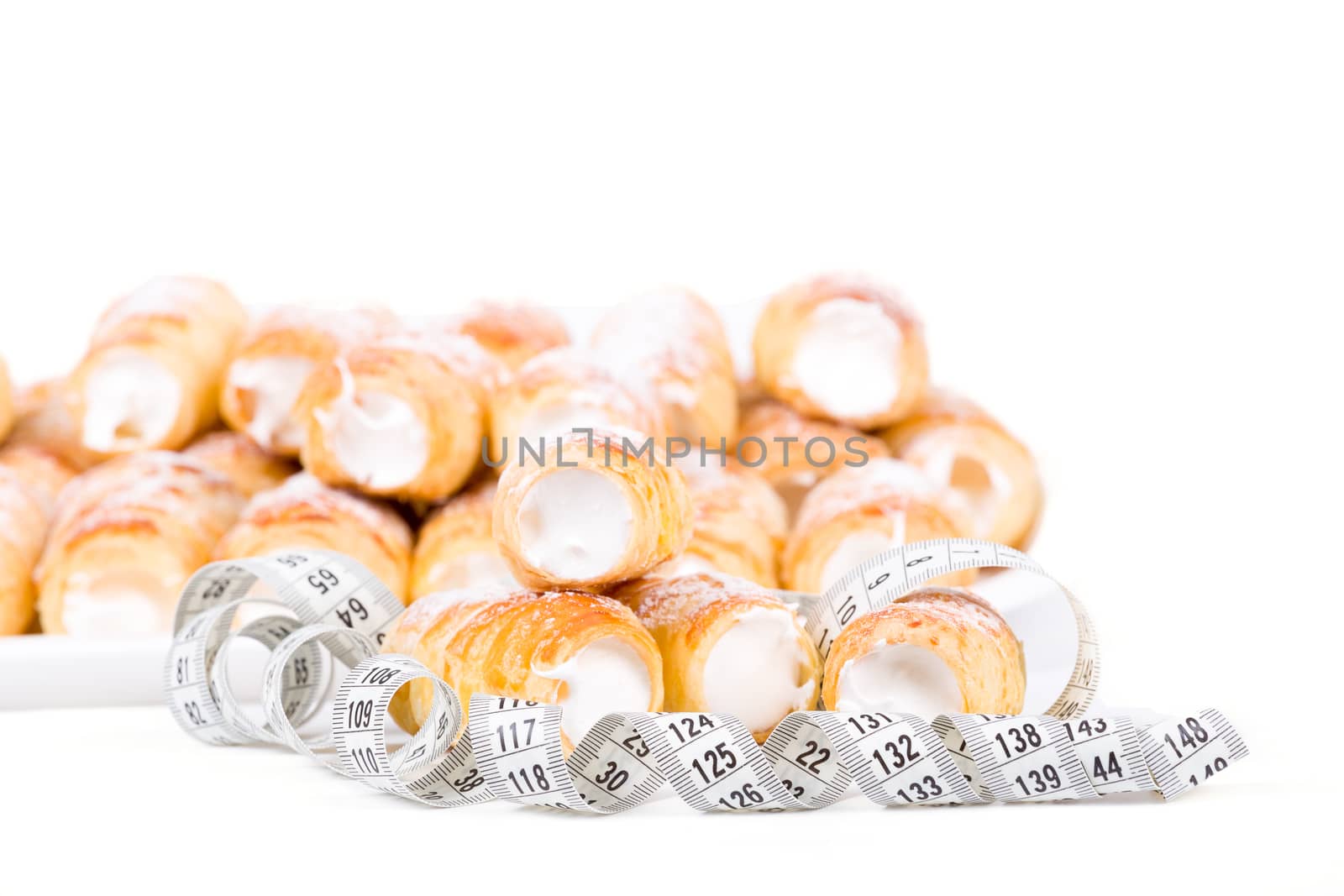 concept of slimming, cakes with measuring tape on white background