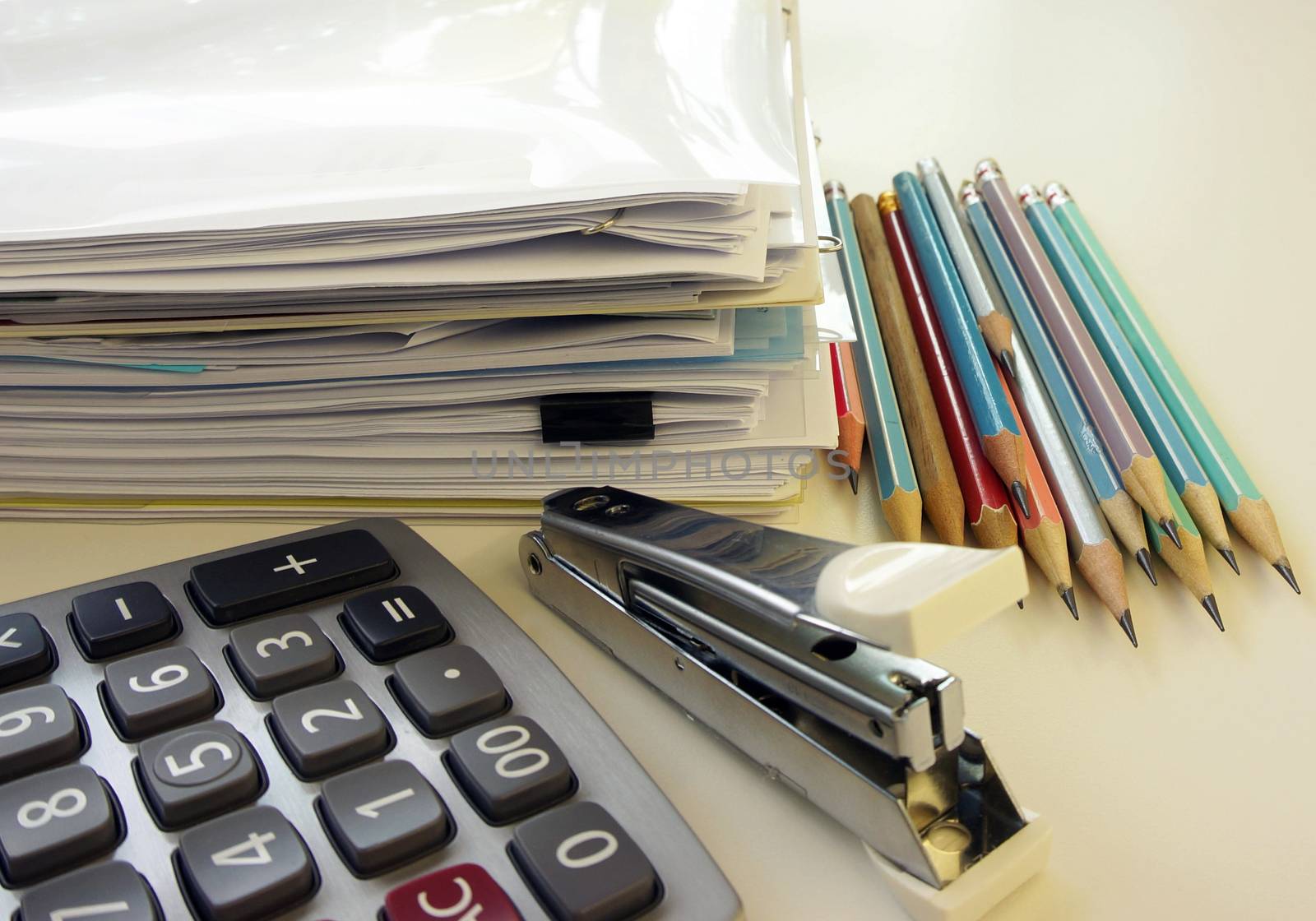 Office report and office equipment, such as calculators, pencil and staples placed on the desk.                               
