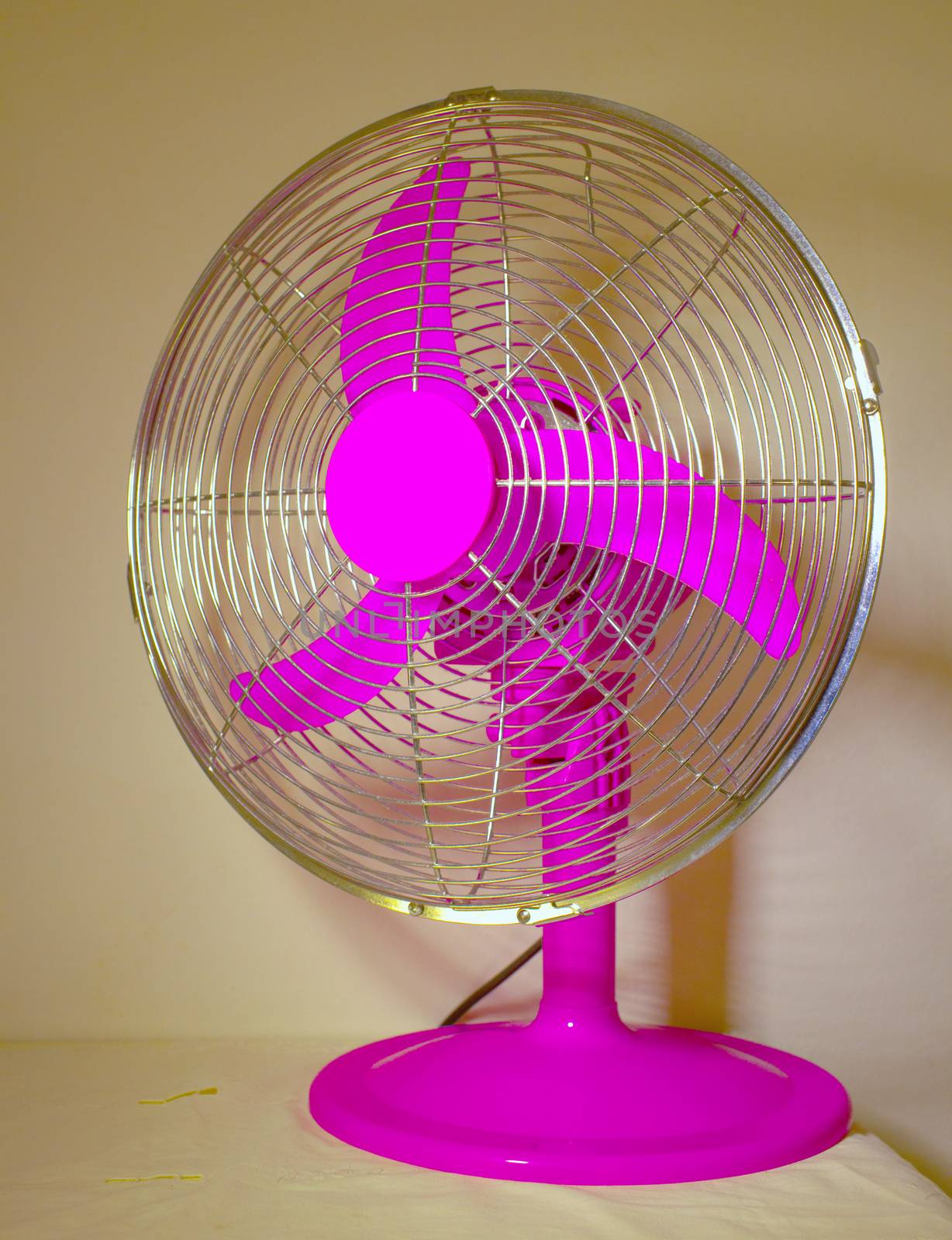 Pink fan with metallic grid over table