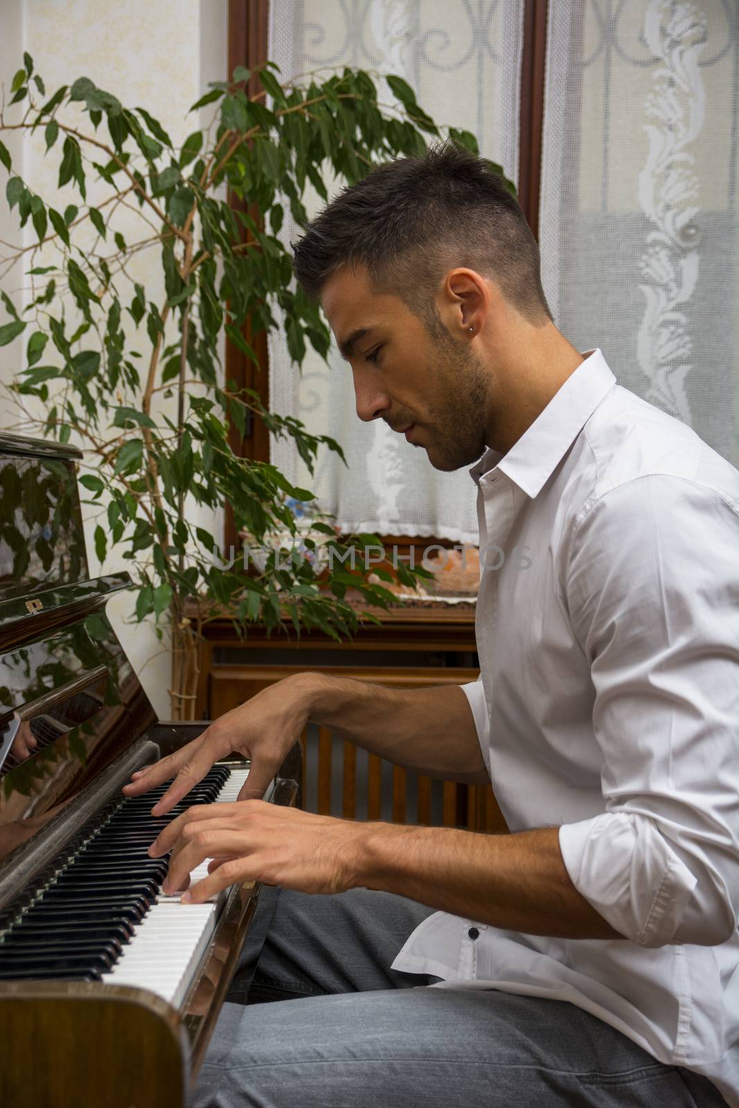 Young handsome male artist playing piano by artofphoto