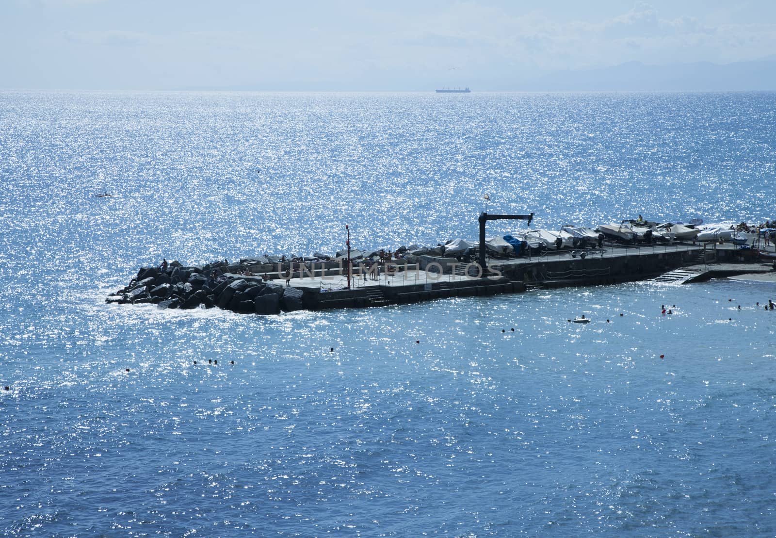 Long pier with rocks extending over the shining sea