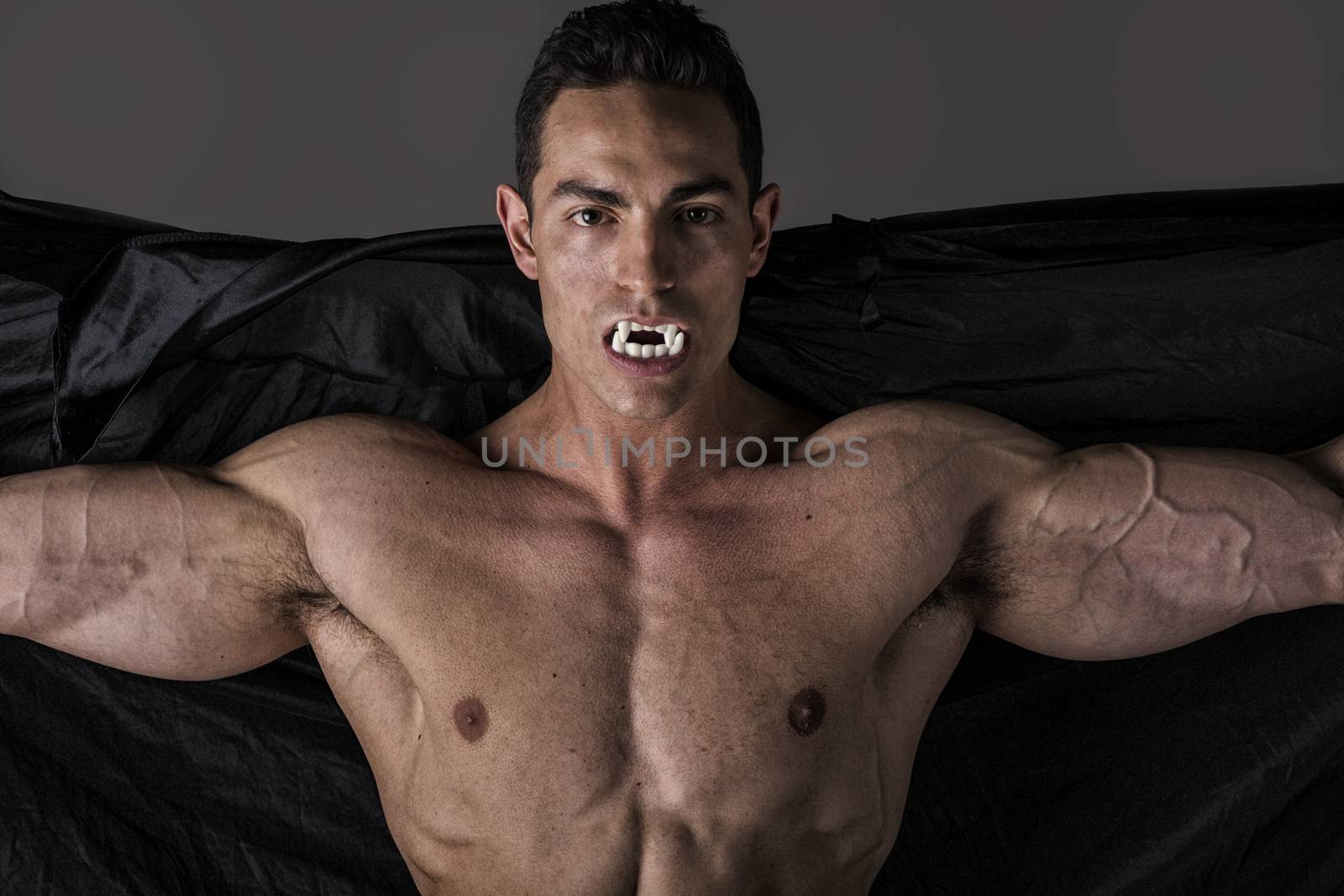 Naked muscular fit young man in briefs posing as a vampire or Dracula by artofphoto