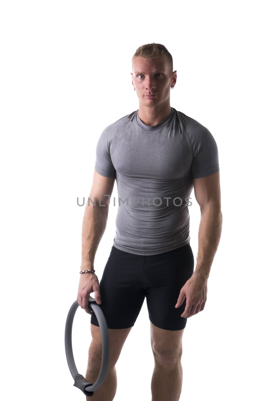 Young muscular man relaxed with Pilates ring in hand, isolated on white