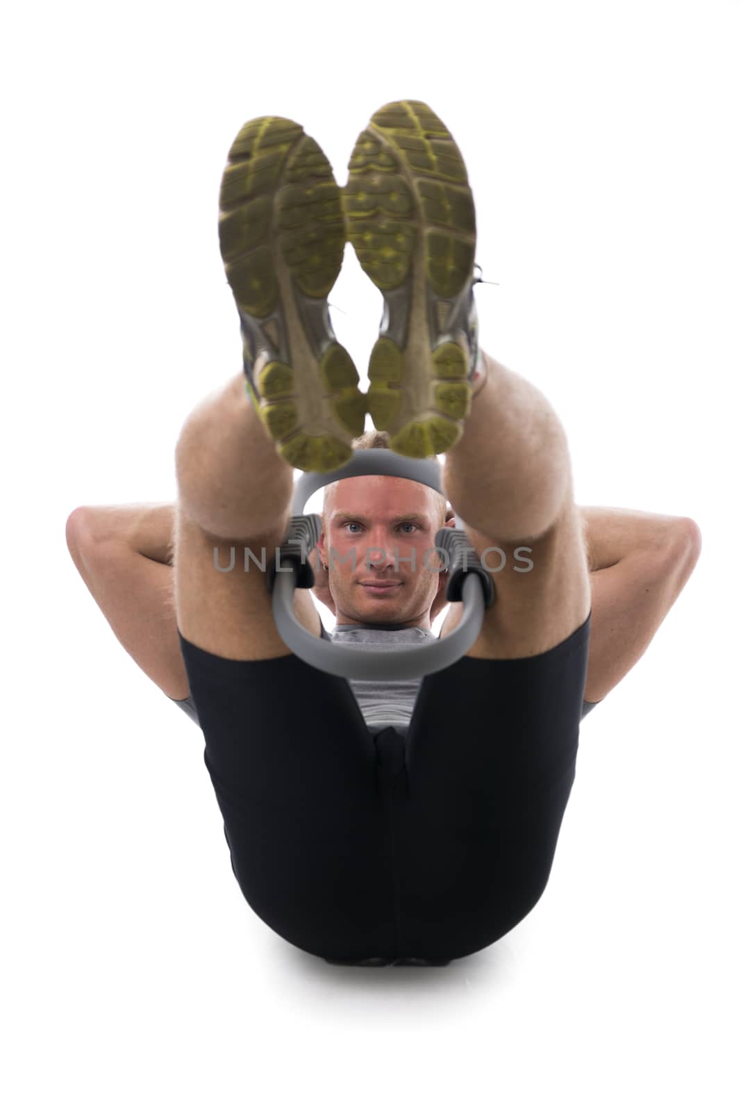 Young muscular man exercising with Pilates ring between legs and knees, isolated on white