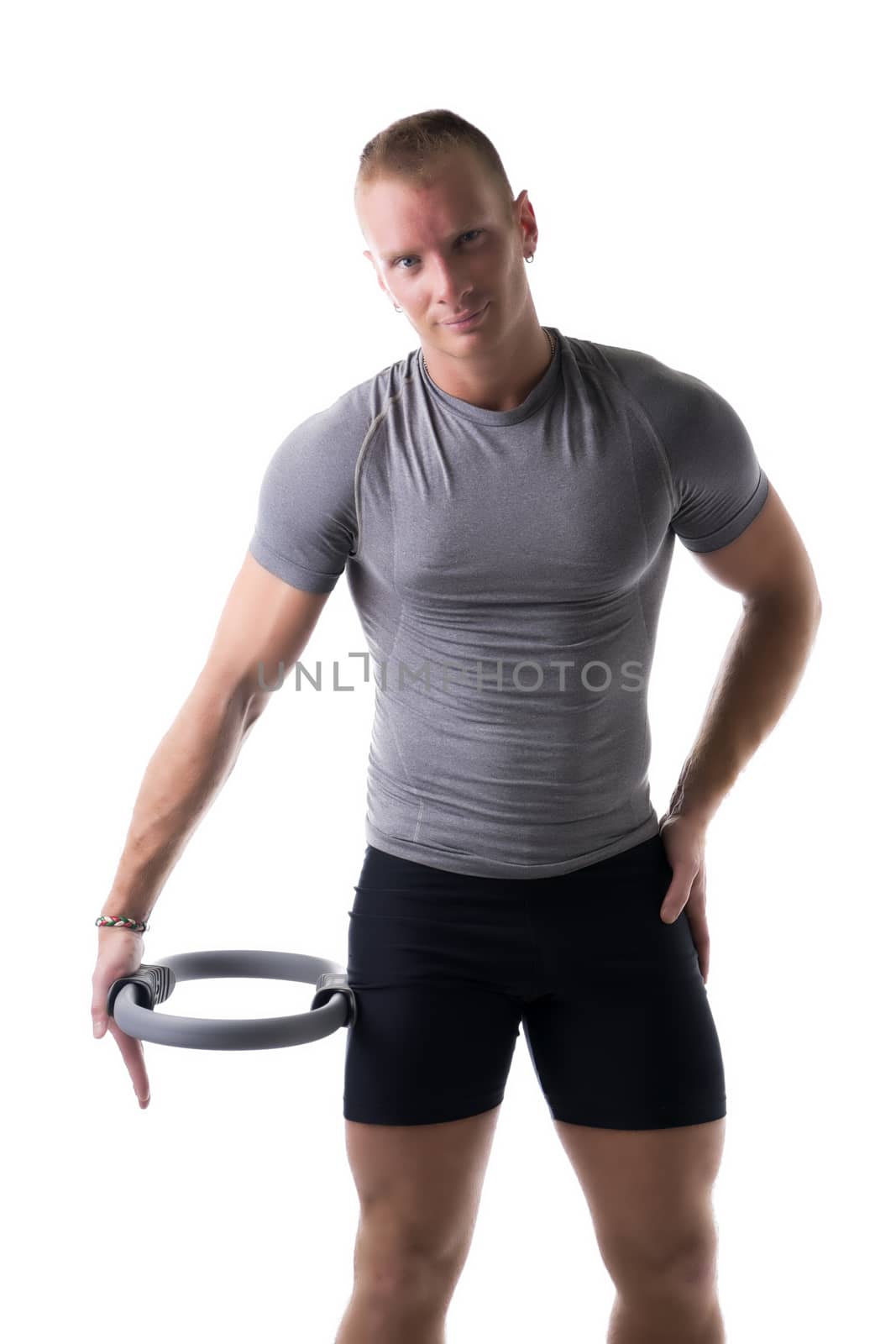 Young muscular man exercising with Pilates ring against thigh, isolated on white