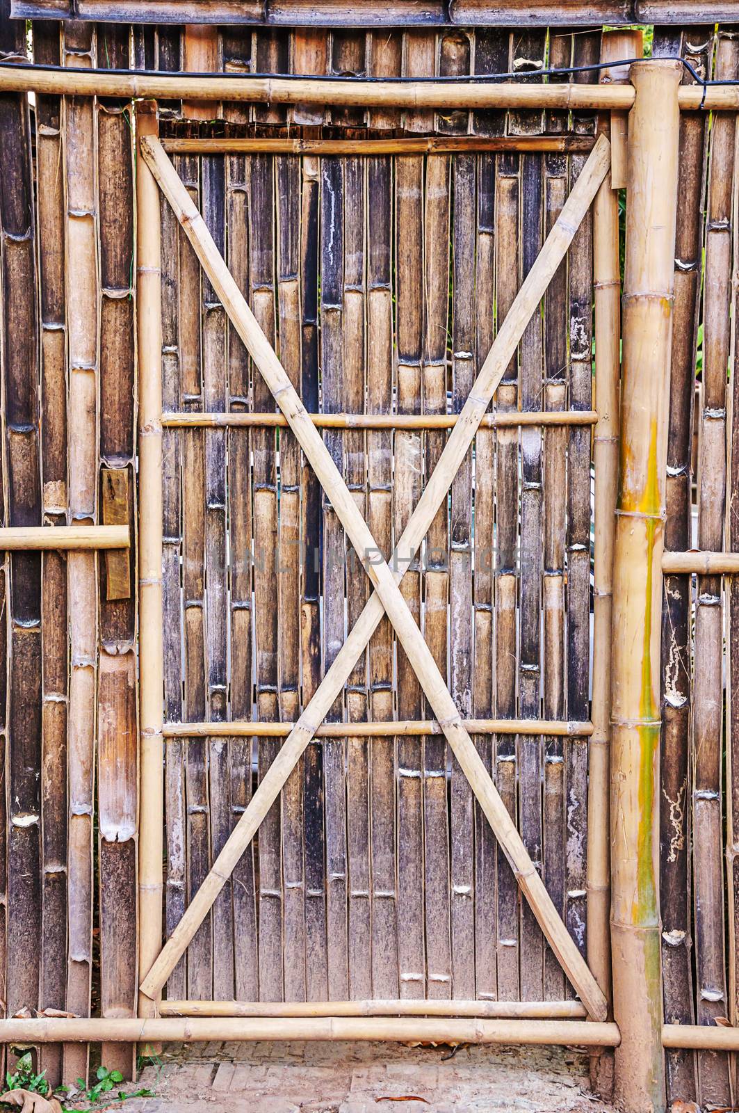 Bamboo door on fence by NuwatPhoto
